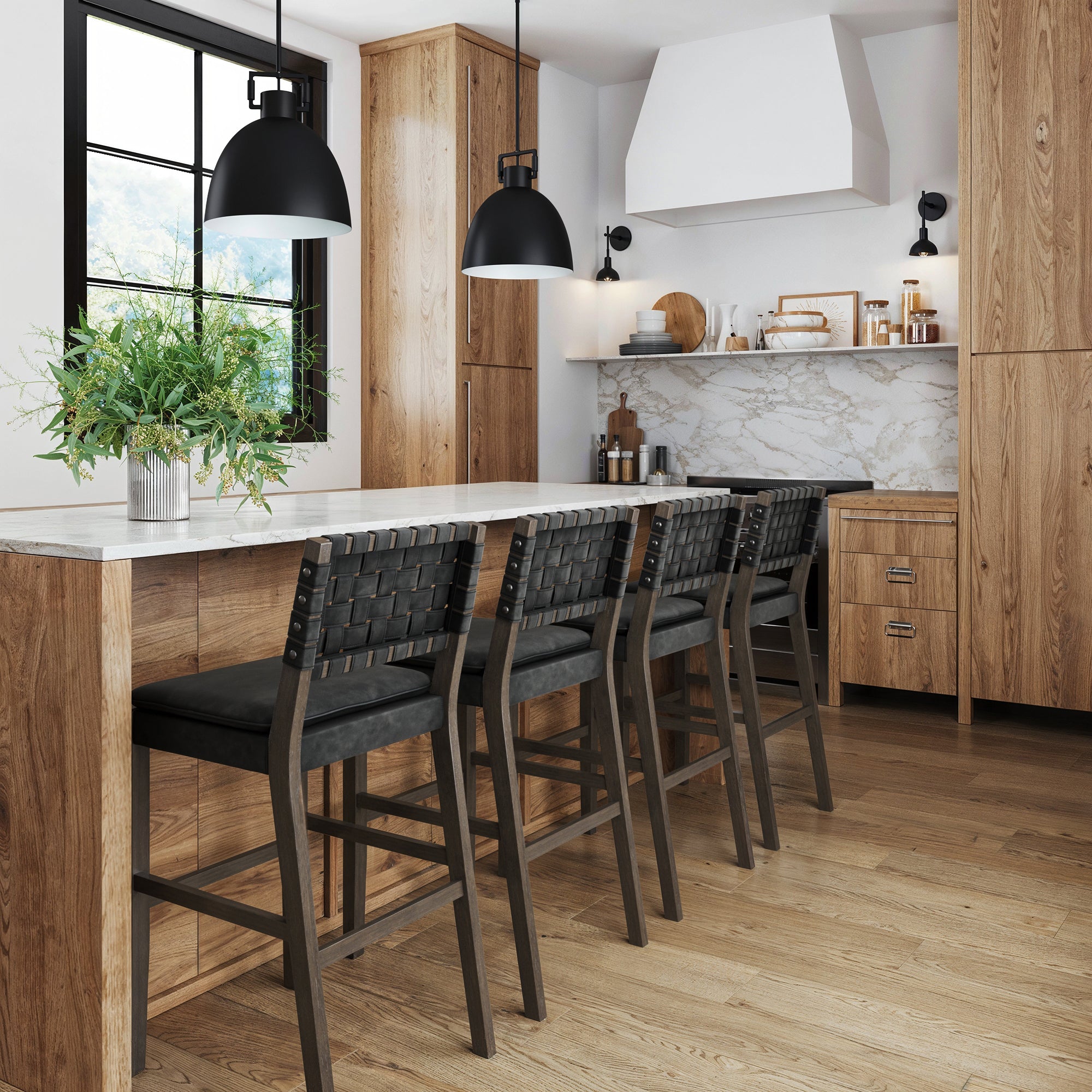 Modern kitchen with wood cabinets, marble backsplash, and a large island with four black woven bar stools. Two black pendant lights hang above the island, and a vase with green foliage sits on the countertop.