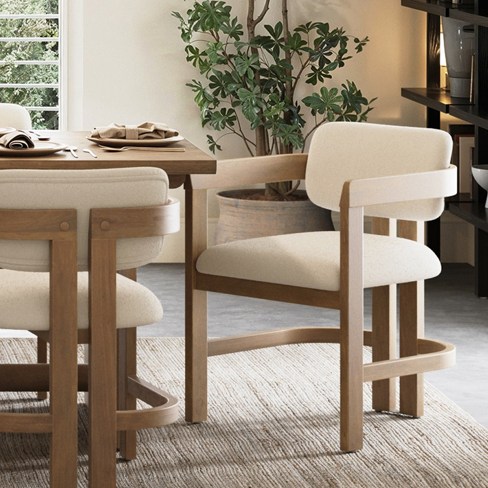 Two light-wood dining chairs with cream-colored upholstered seats and backrests sit at a wooden dining table.
