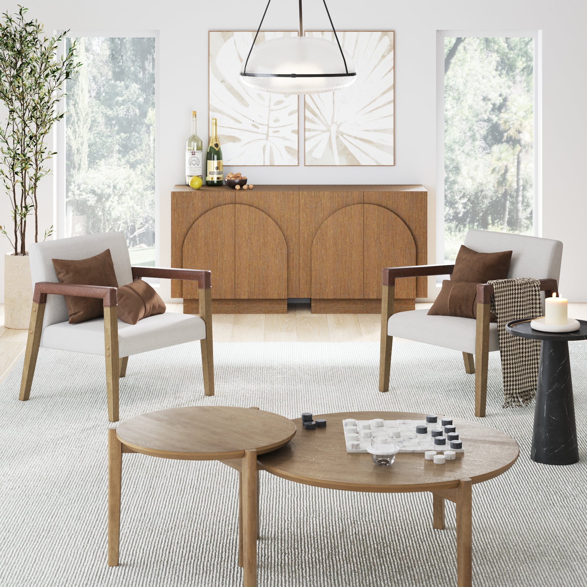 A modern living room with two armchairs, a round wooden coffee table with a game board, a side table with a candle, a wooden sideboard with decor, abstract wall art, and large windows letting in natural light.