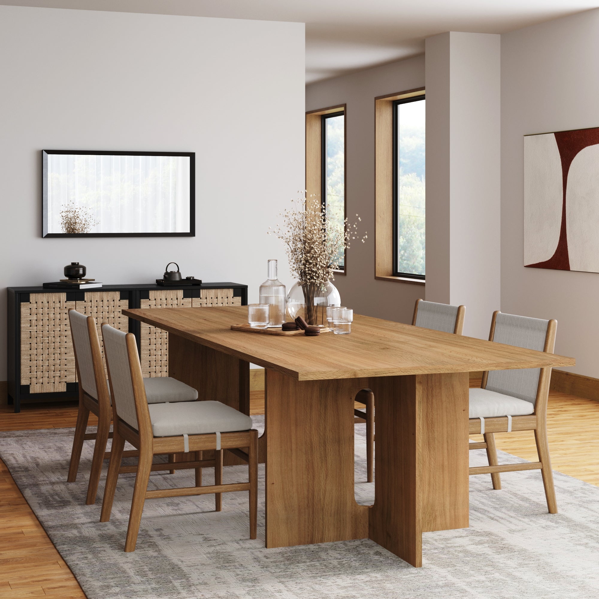 A modern dining room features a wooden table, four Nathan James Woven Rope Back Dining Chairs in brushed light brown, a sideboard with wicker panels, decorative vases, and large windows that fill the cozy space with natural light and minimalist charm.