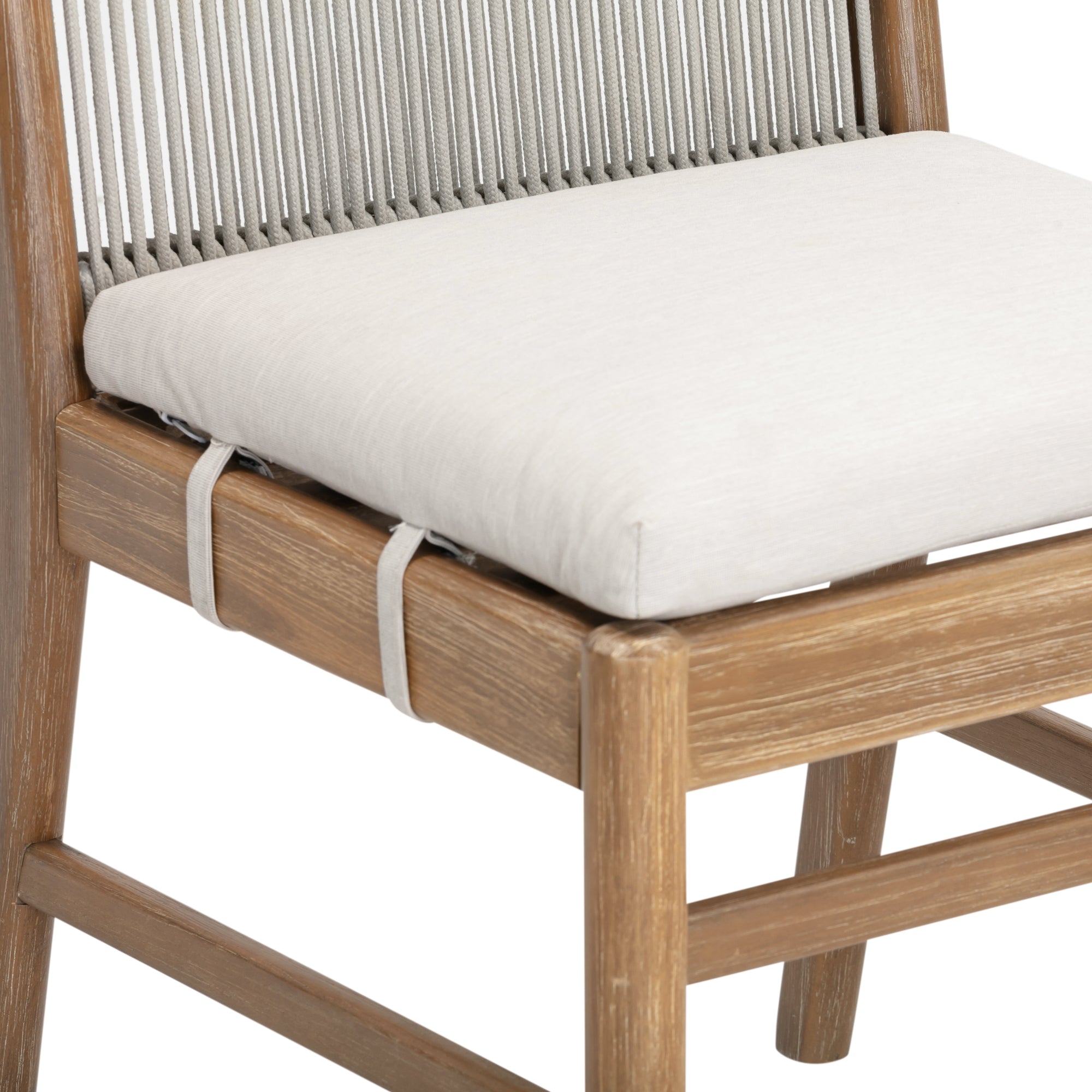 A close-up of a wooden chair with a light beige cushioned seat and a backrest made of vertical, taut, gray cords. The cushion is secured to the chair with two fabric straps.