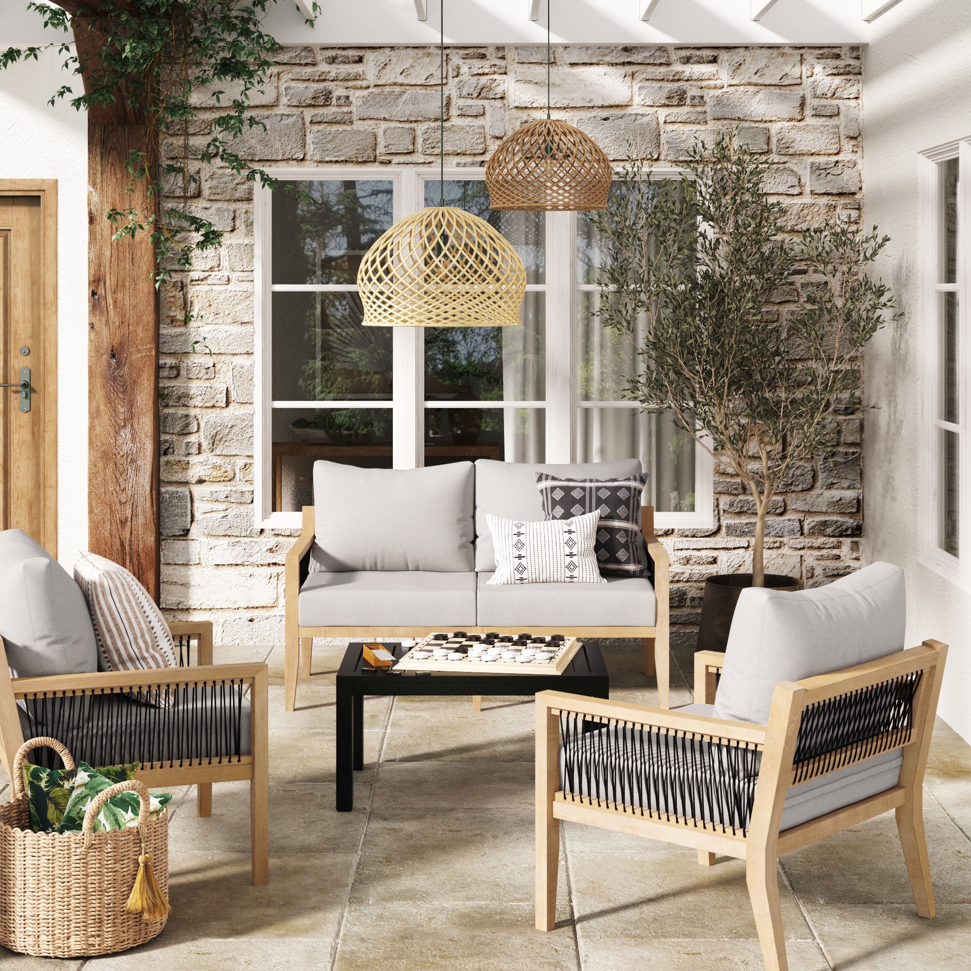 Modern patio featuring the Nathan James Outdoor 4 Piece Wood Patio Set—acacia chairs, gray weather-resistant cushions, black coffee table—styled with a woven basket, rattan pendant lights, stone wall, window, potted olive tree and decorative pillows.