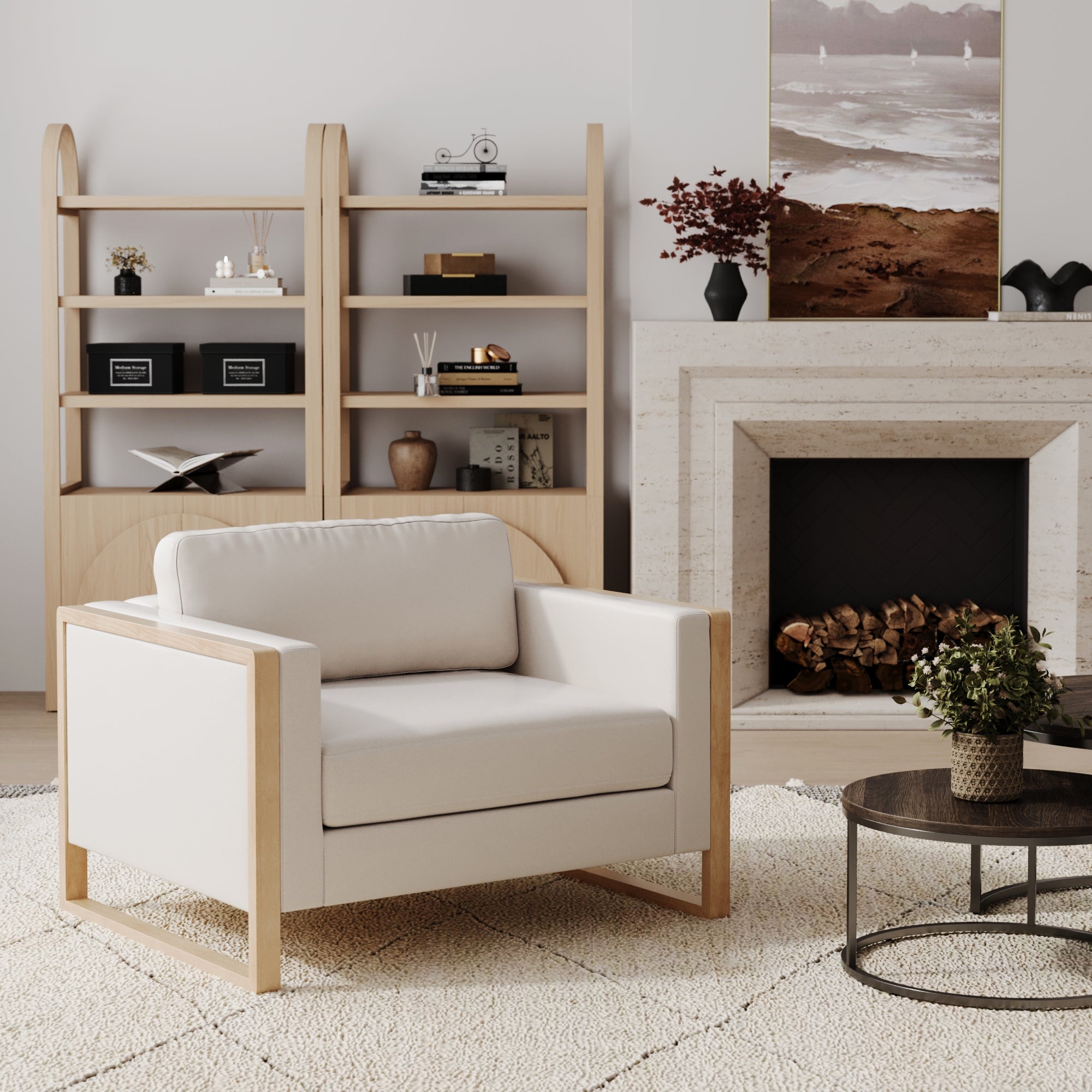 A modern living room features the Nathan James Soft Fabric Wood Frame Armchair in Bisque, a modular sofa, round coffee table, fireplace with logs, bookshelf displaying decor, and landscape art above the mantel. Neutral tones and minimalist style complete the look.