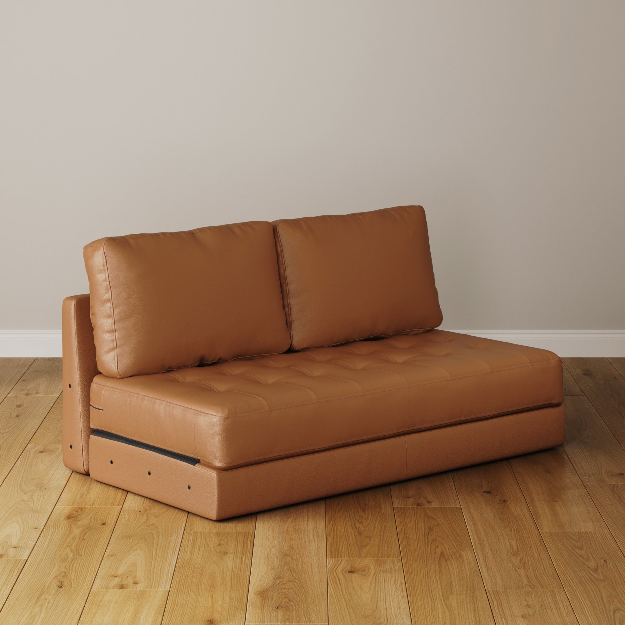 The Nathan James Mid-Century Tufted Leather Sofa Bench Seat in camel sits on a light wooden floor against a plain beige wall.