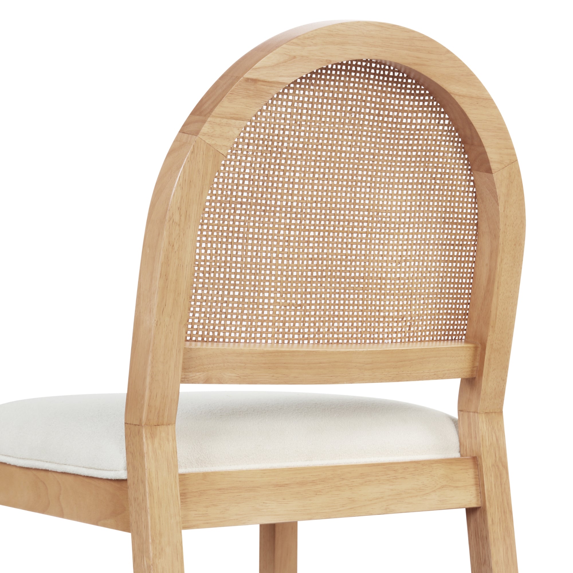 A close-up of a wooden chair with a rounded, woven cane backrest and a cushioned white seat. The chair has a natural light wood finish.