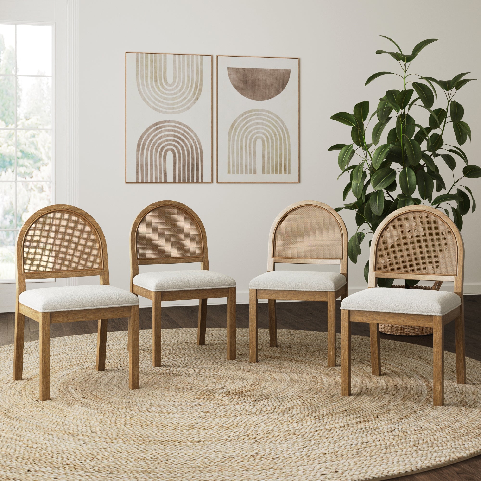 Four Nathan James Boucle & Rattan Dining Chairs in light brown (set of 4) are arranged in a semi-circle on a woven rug, with a large potted plant and two abstract geometric art pieces hanging on the wall behind.