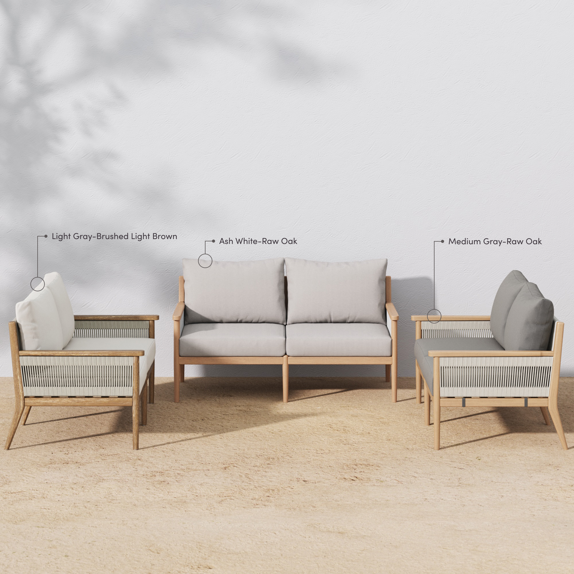 Four-piece outdoor seating set with two armchairs, a loveseat, and a coffee table on a sandy surface. The frames are light wood, and the cushions are various shades of gray. Labels indicate cushion and wood colors.