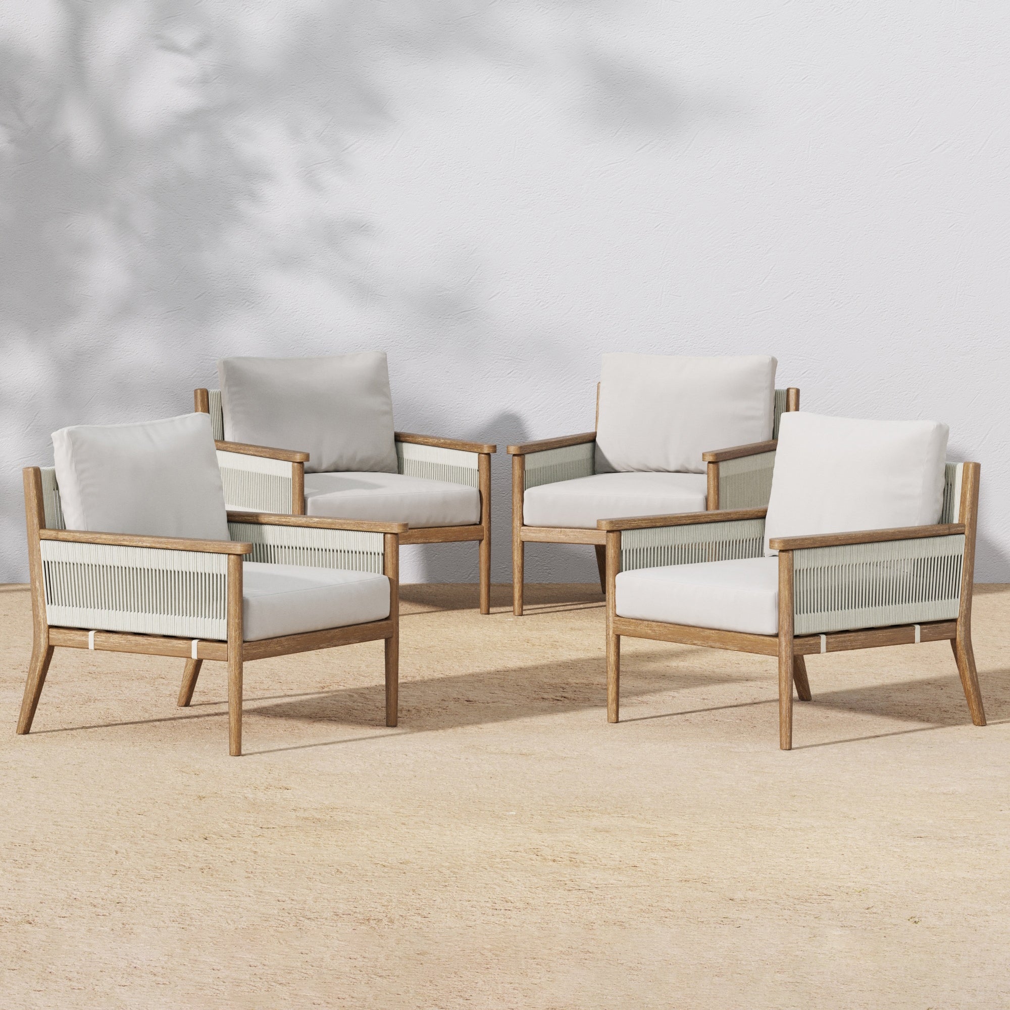 Four Nathan James Outdoor Wood & Rope Patio Arm Chairs in light gray, each with removable washable cushion covers, are arranged outdoors against a white wall with soft tree shadows. Set includes 4 weather-resistant chairs.