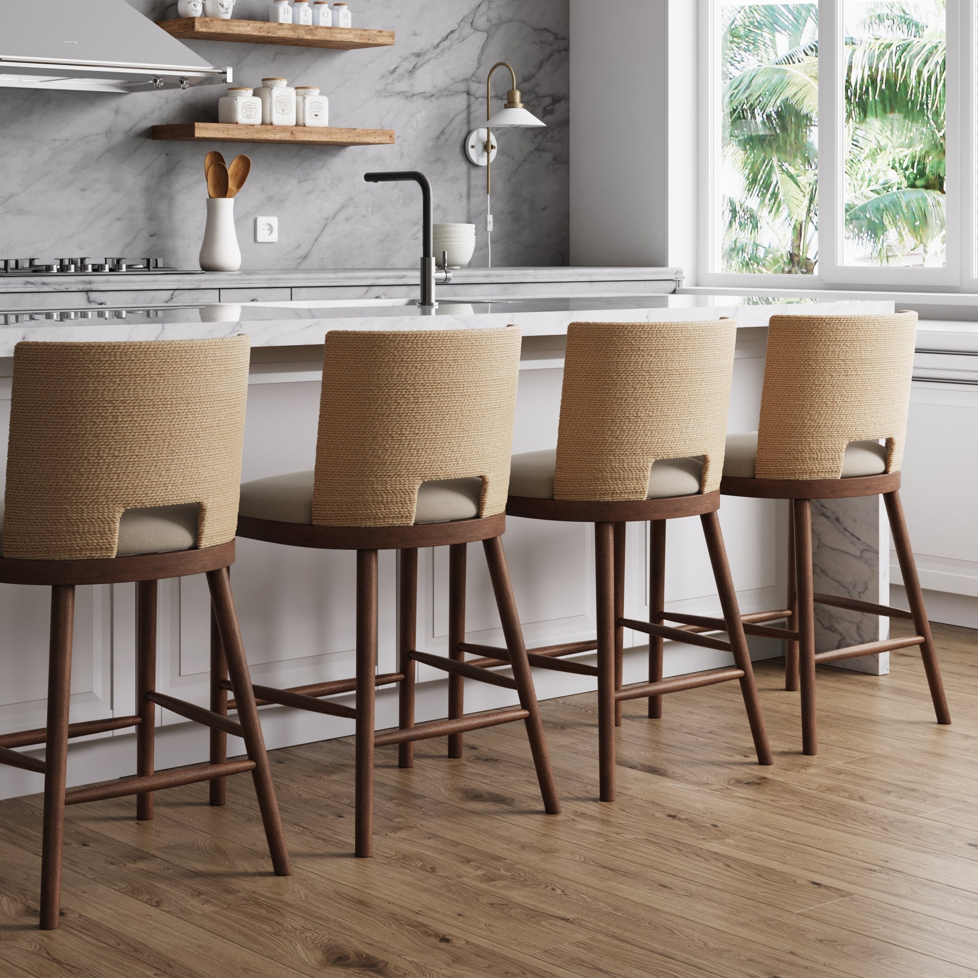 Four Nathan James Seagrass Rope Back Counter Bar Stools in medium brown are lined up at a marble kitchen island in a modern kitchen with a marble backsplash, wood floors, and large windows overlooking green trees.