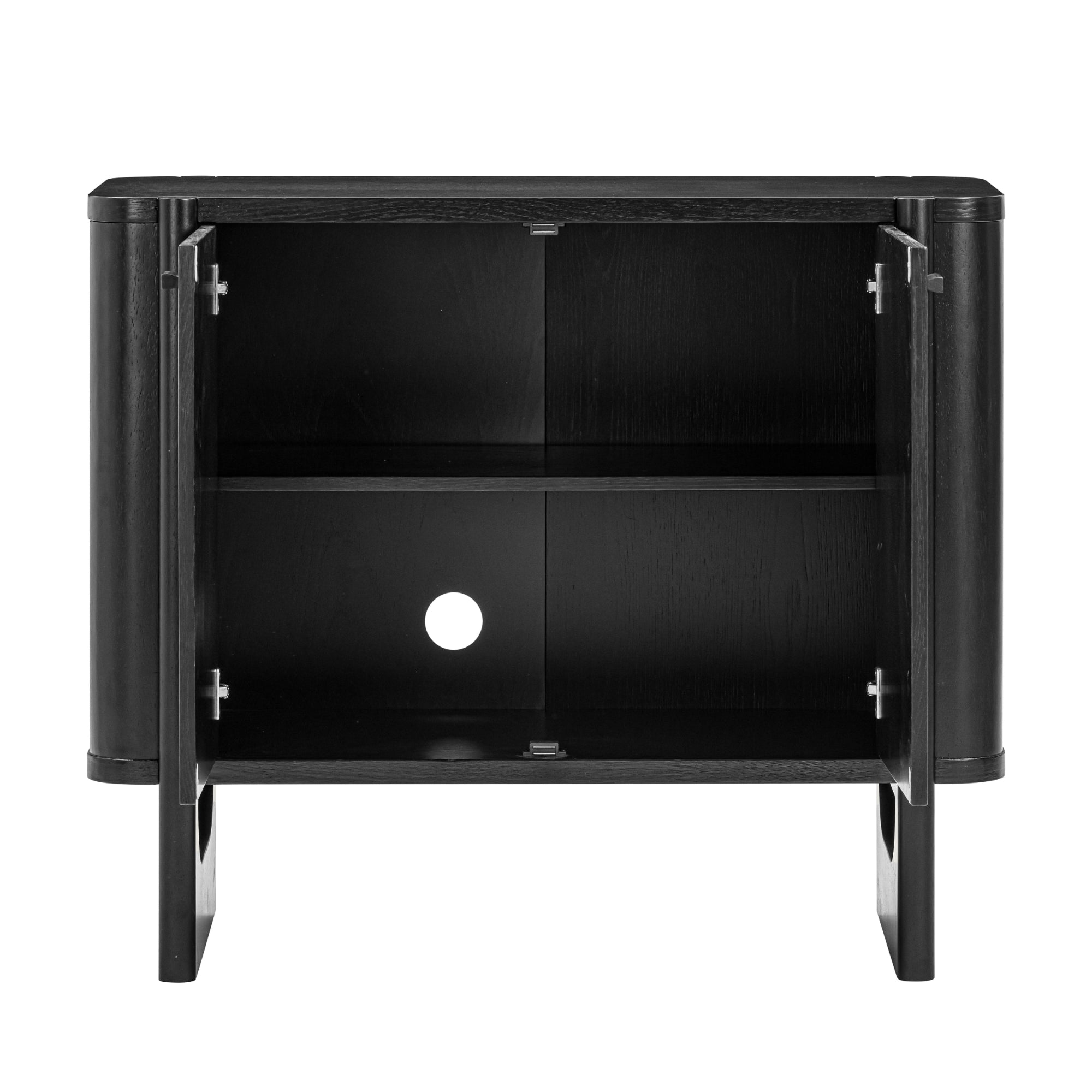 A black wooden cabinet with two open doors, a central shelf dividing the interior, and a round cable management hole in the back panel. The cabinet stands on four short legs.