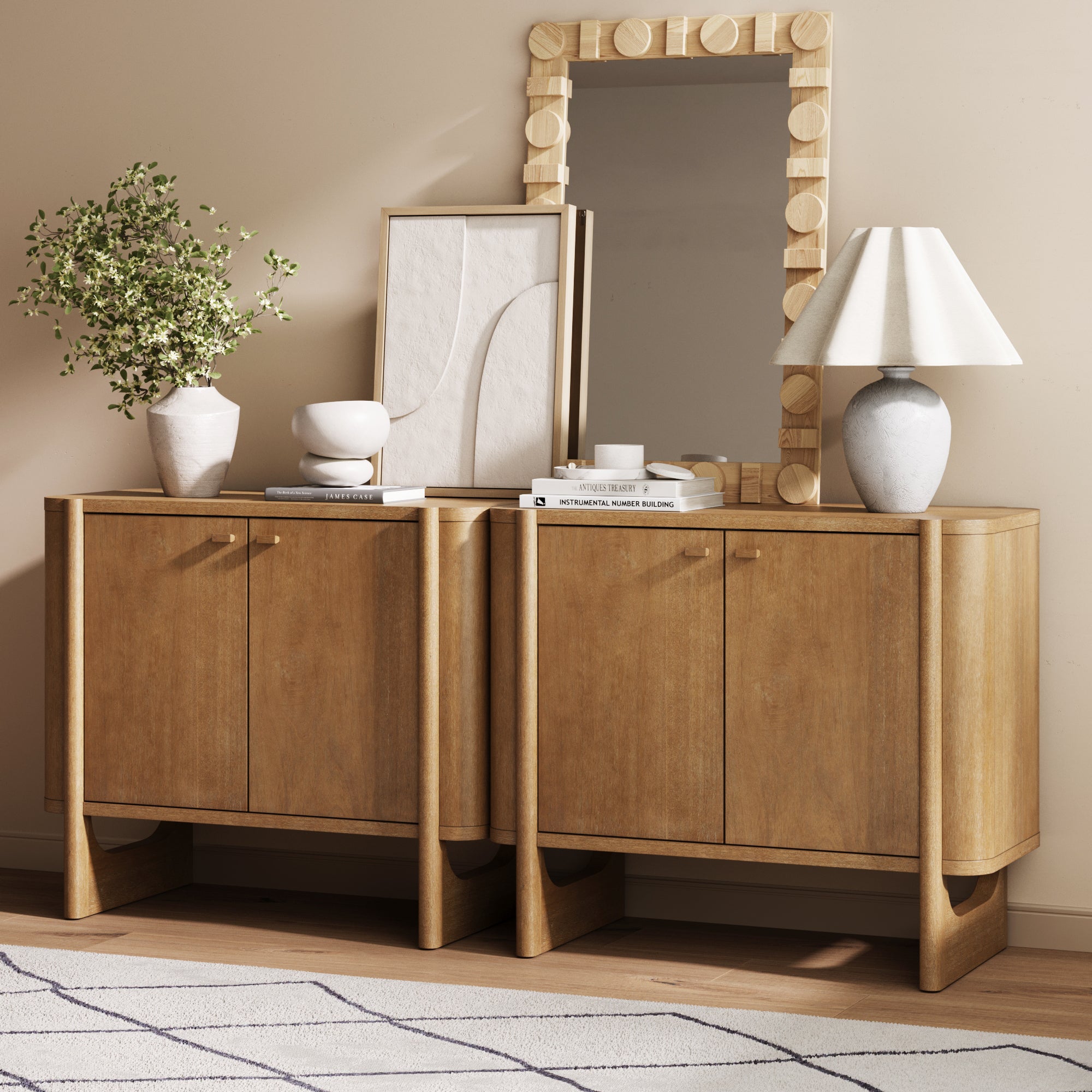 The Nathan James Mid-Century Modern Solid Wood Accent Cabinet or TV Stand in light brown (set of 2) stands on a light rug against a neutral wall, styled with modern decor like books, vases, a lamp, and a mirror—ideal for mid-century spaces.