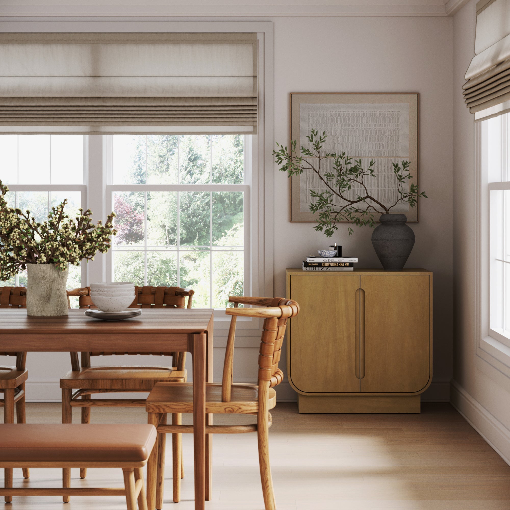 Bright dining room with a wooden table, chairs, and bench. Large windows with beige roman shades bring in light. The Nathan James Wood Veneer Arched Accent Cabinet in light brown displays a tall vase, with framed wall art above it.