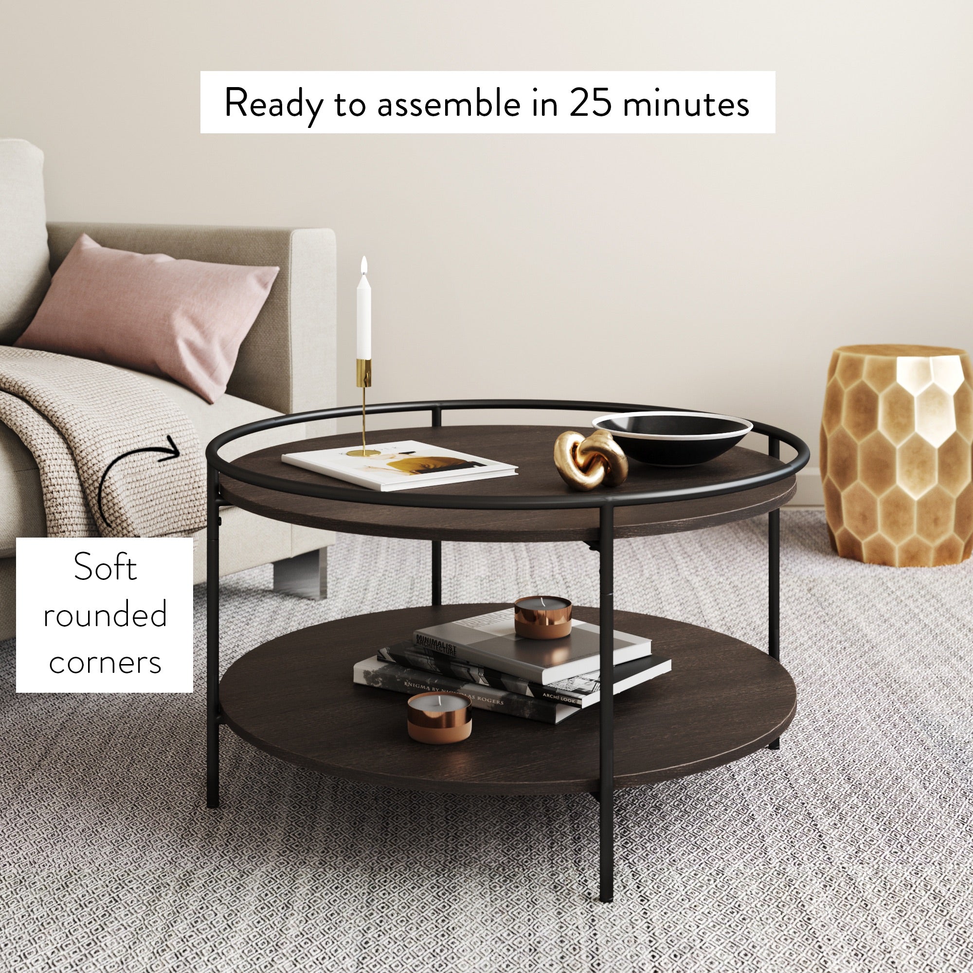 A modern round coffee table with two dark wooden shelves and black metal legs is shown in a living room. Text notes Soft rounded corners and Ready to assemble in 25 minutes. Decor items rest on both shelves.