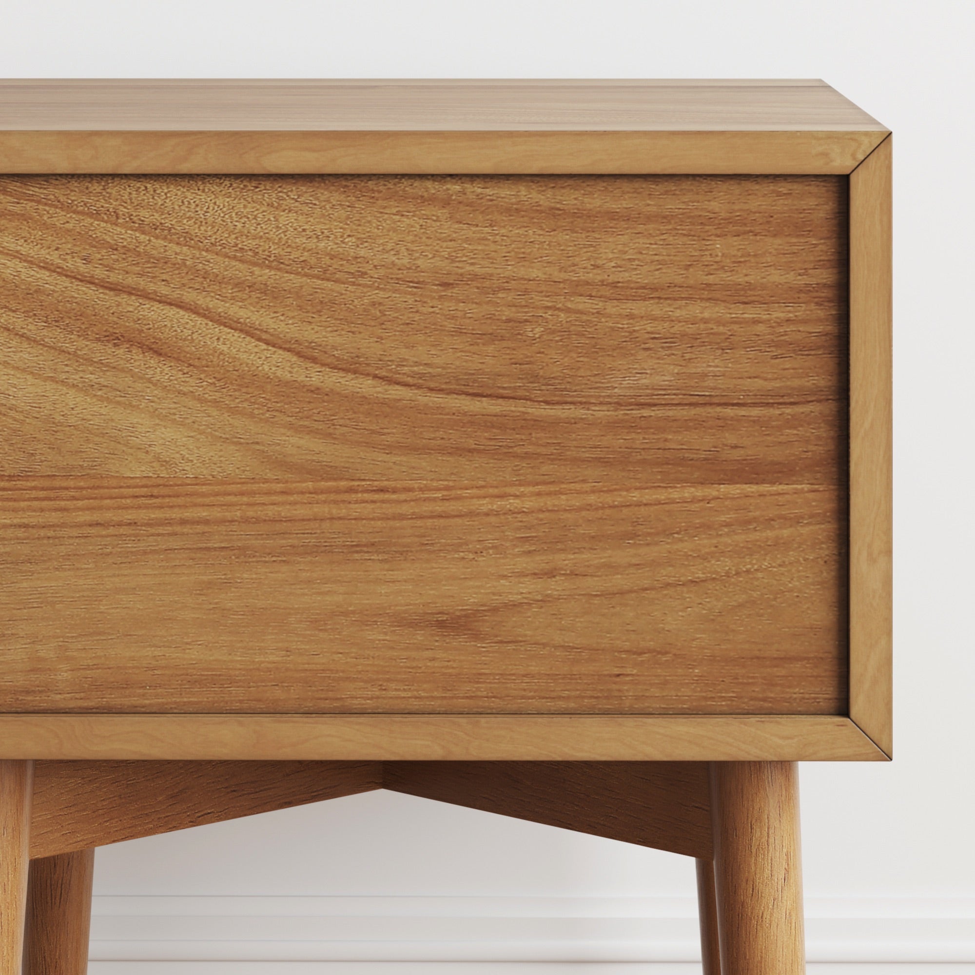 Close-up of a modern wooden cabinet with a smooth, natural finish. The cabinet has clean lines and stands on four rounded legs, set against a white wall and floor.