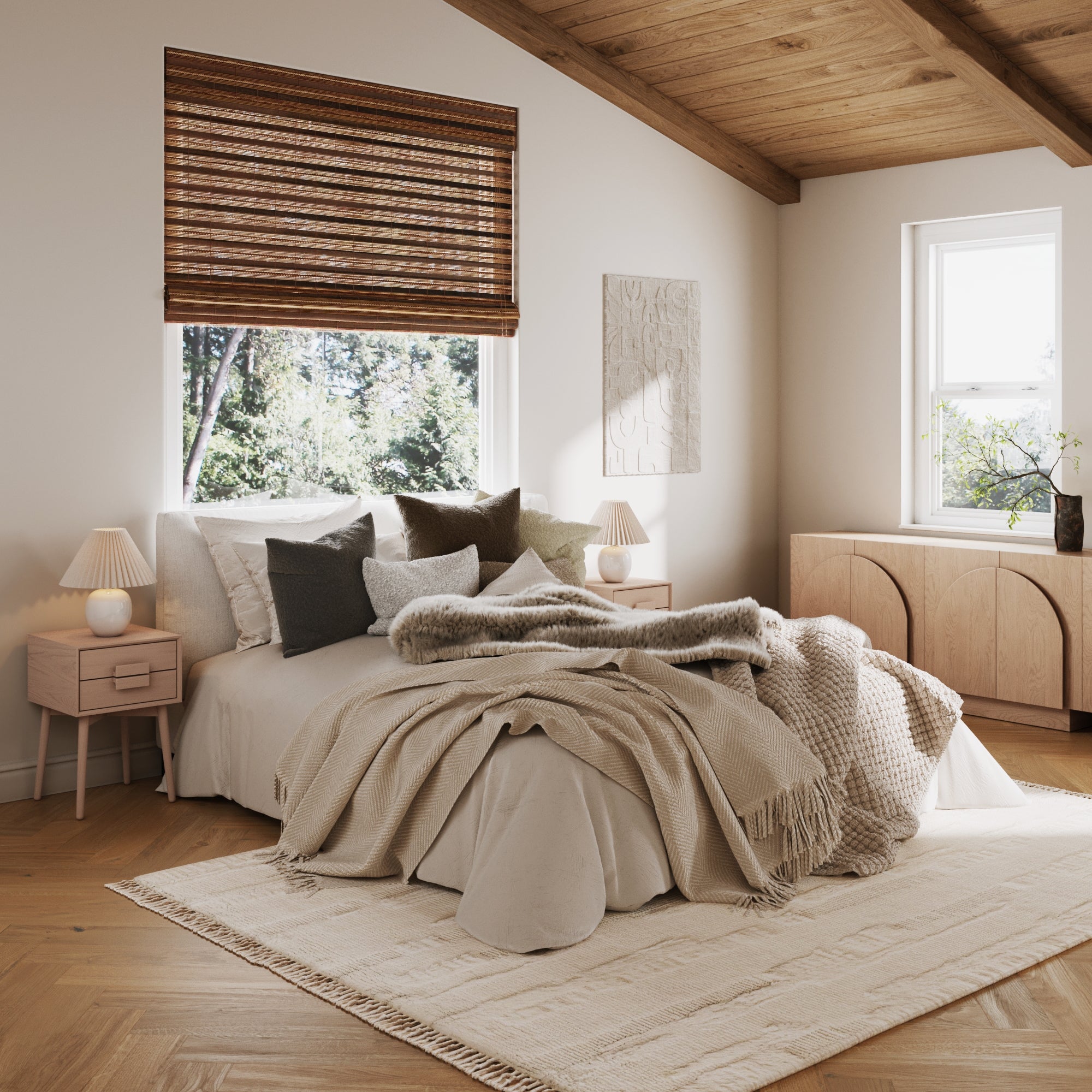A cozy bedroom with a bed in neutral blankets and pillows, Nathan James Mid-Century Wood Handle Nightstands in raw oak (set of 2) with lamps, a light rug, wooden blinds, large windows, and minimalist decor for a warm, inviting feel.