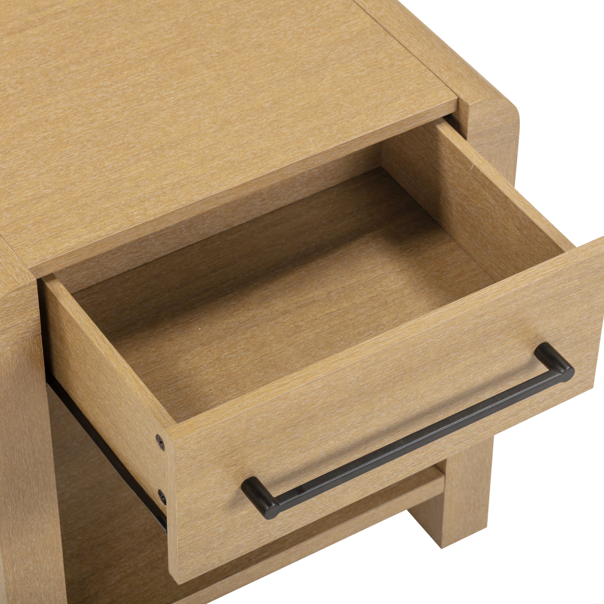 A close-up view of a light wood nightstand with a single drawer pulled open, showing an empty interior. The drawer has a long black metal handle.
