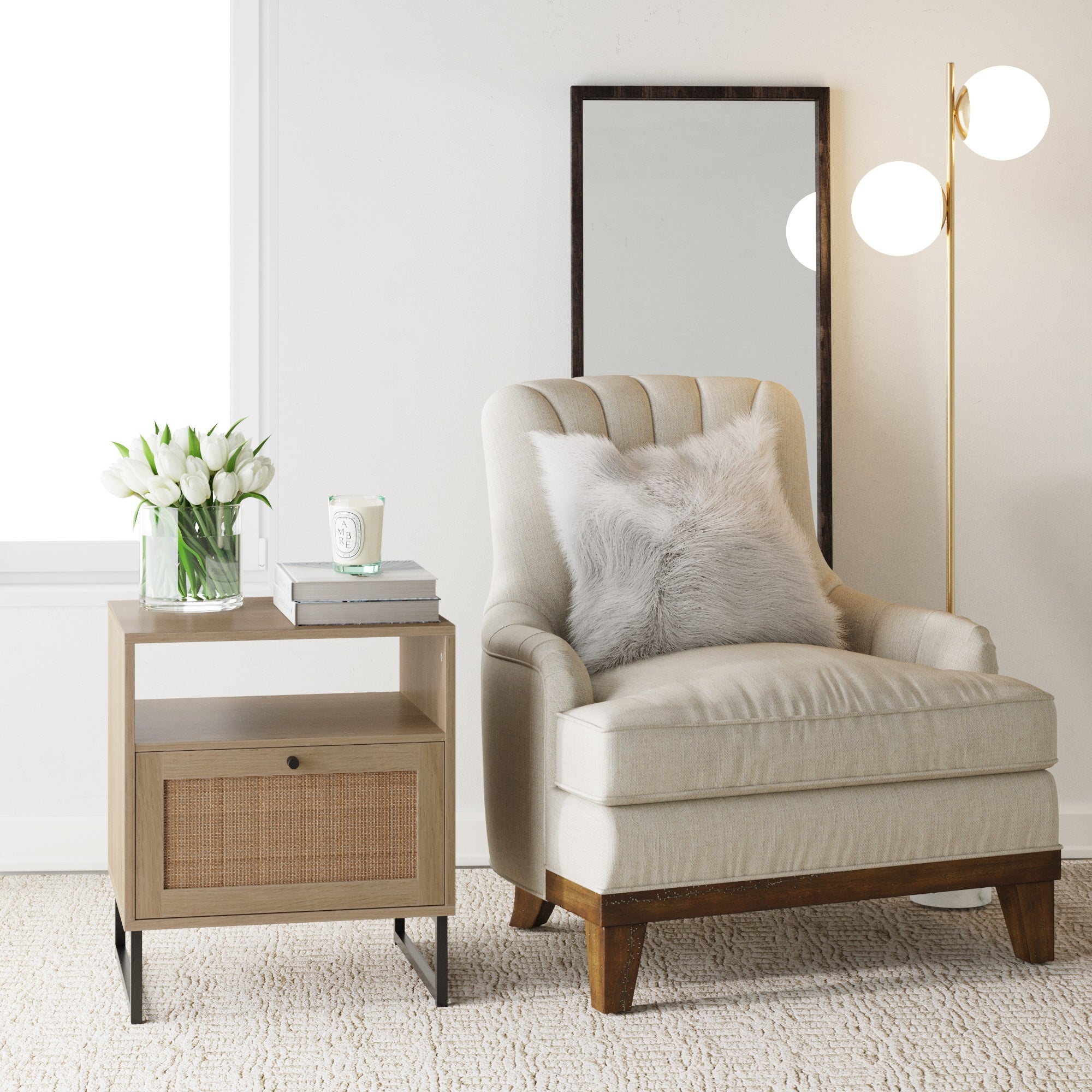 A cozy beige armchair with a fluffy gray pillow sits beside a light wood side table holding a vase of white tulips and a candle. A floor lamp and a mirror complete the modern, elegant room decor.