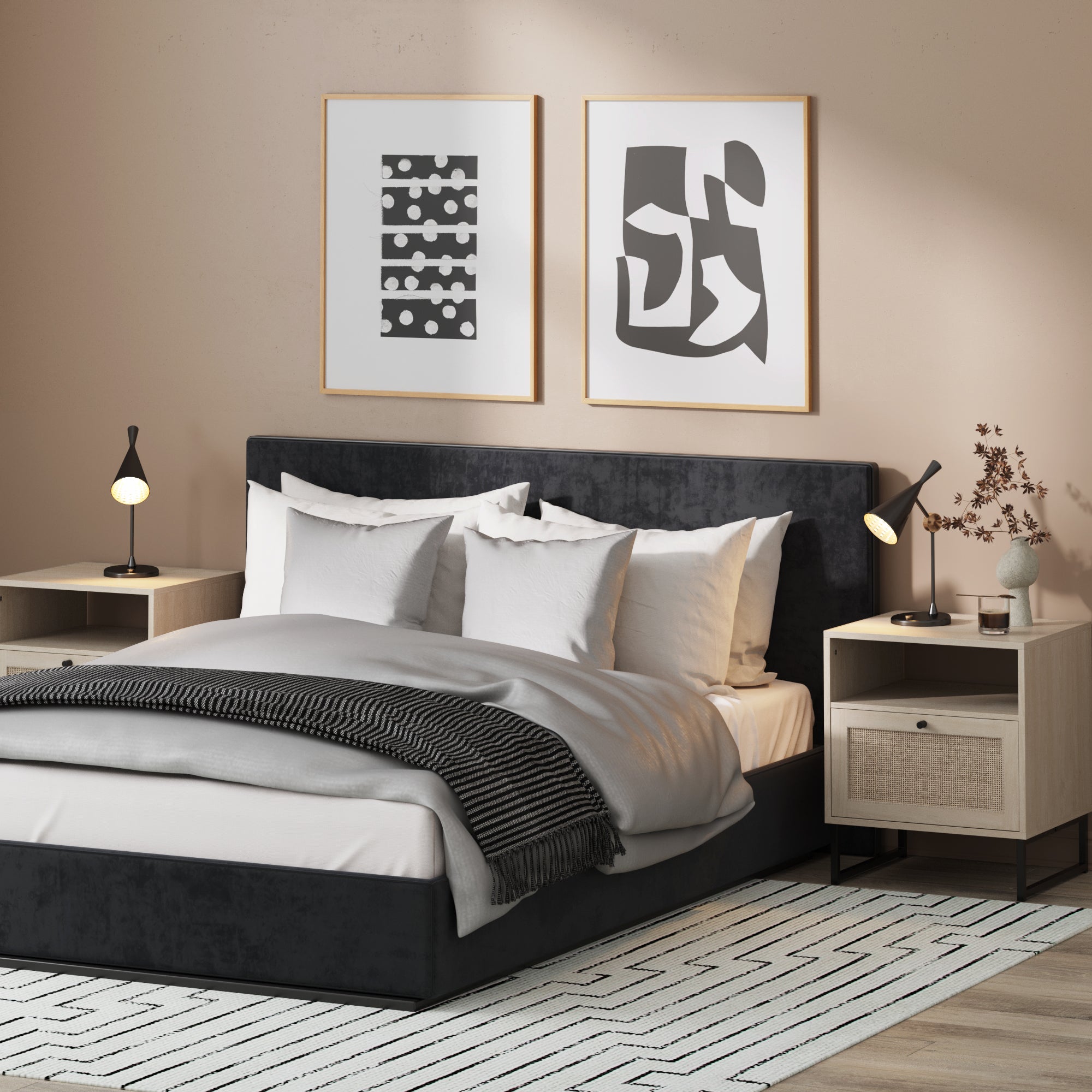 A modern bedroom with a dark upholstered bed, white and gray bedding, two light wood nightstands, black lamps, abstract art on the wall, and a geometric rug on the floor. Dried branches in a vase sit on one nightstand.