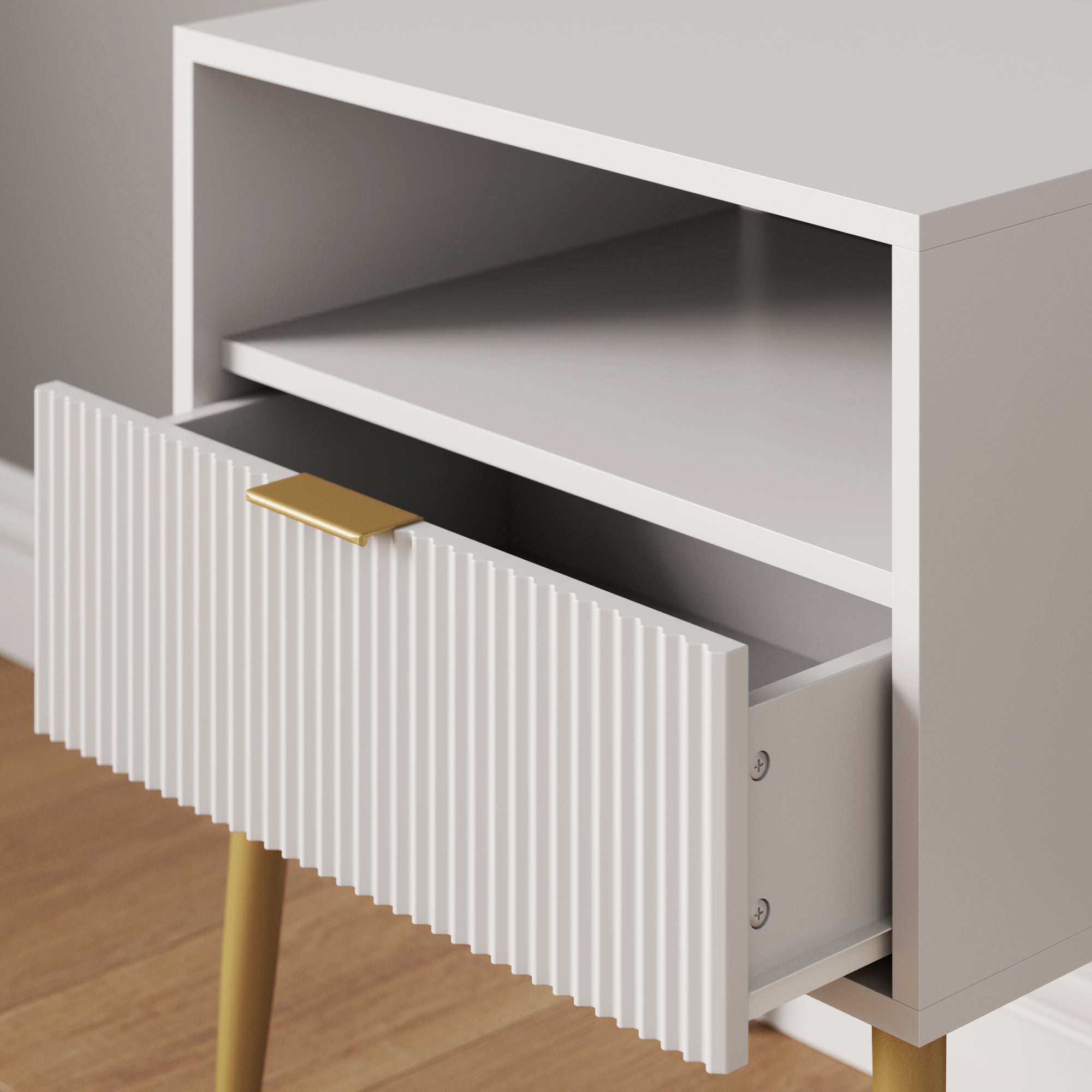 A modern white nightstand with gold legs, featuring an open shelf and a single drawer with a textured front and gold handle, standing on a wooden floor. The drawer is partially open.