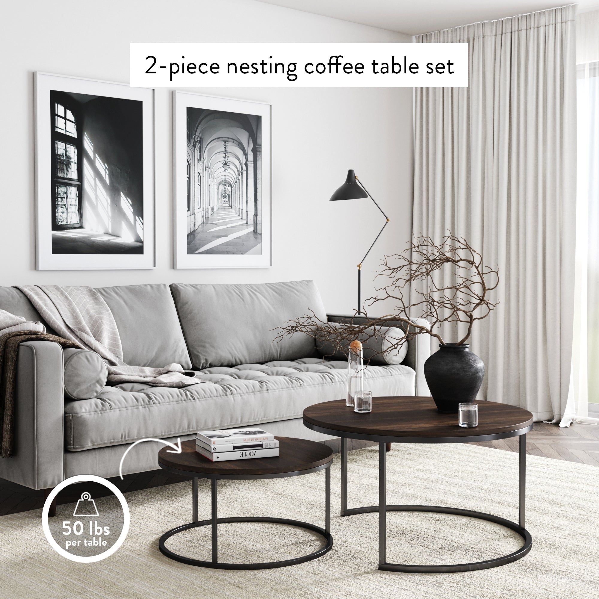 Modern living room with a gray sofa, two black-and-white framed photos on the wall, and a 2-piece round nesting coffee table set with dark wood tops and black metal frames. A vase with twigs sits on the larger table.