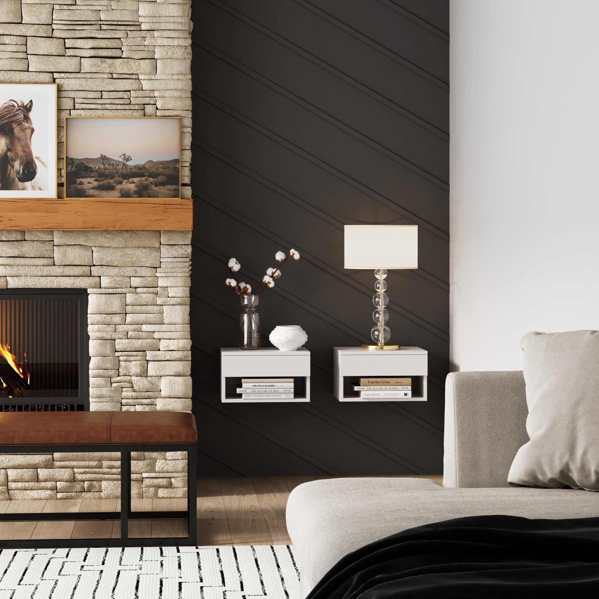 A modern living room with a stone fireplace, wooden mantel displaying framed art, a dark diagonal accent wall, two floating white shelves with decor, a lamp, and a light gray sofa in the foreground.