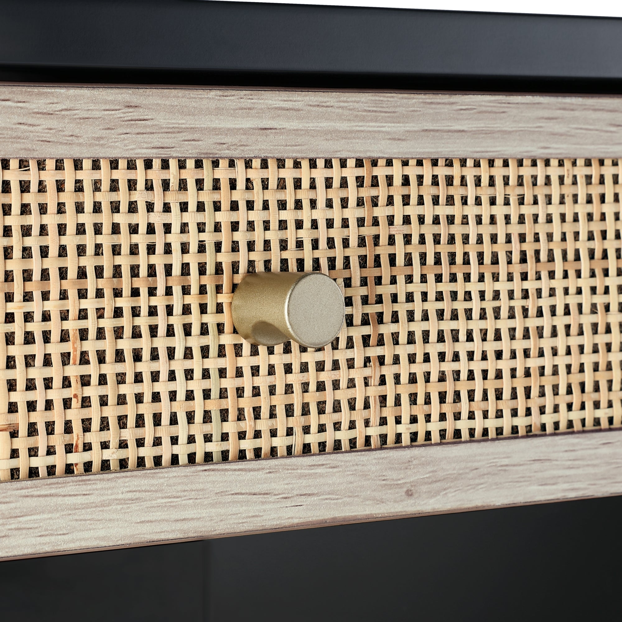 Close-up of a drawer with a woven rattan front panel, framed by light-colored wood, featuring a round, gold-colored knob in the center.