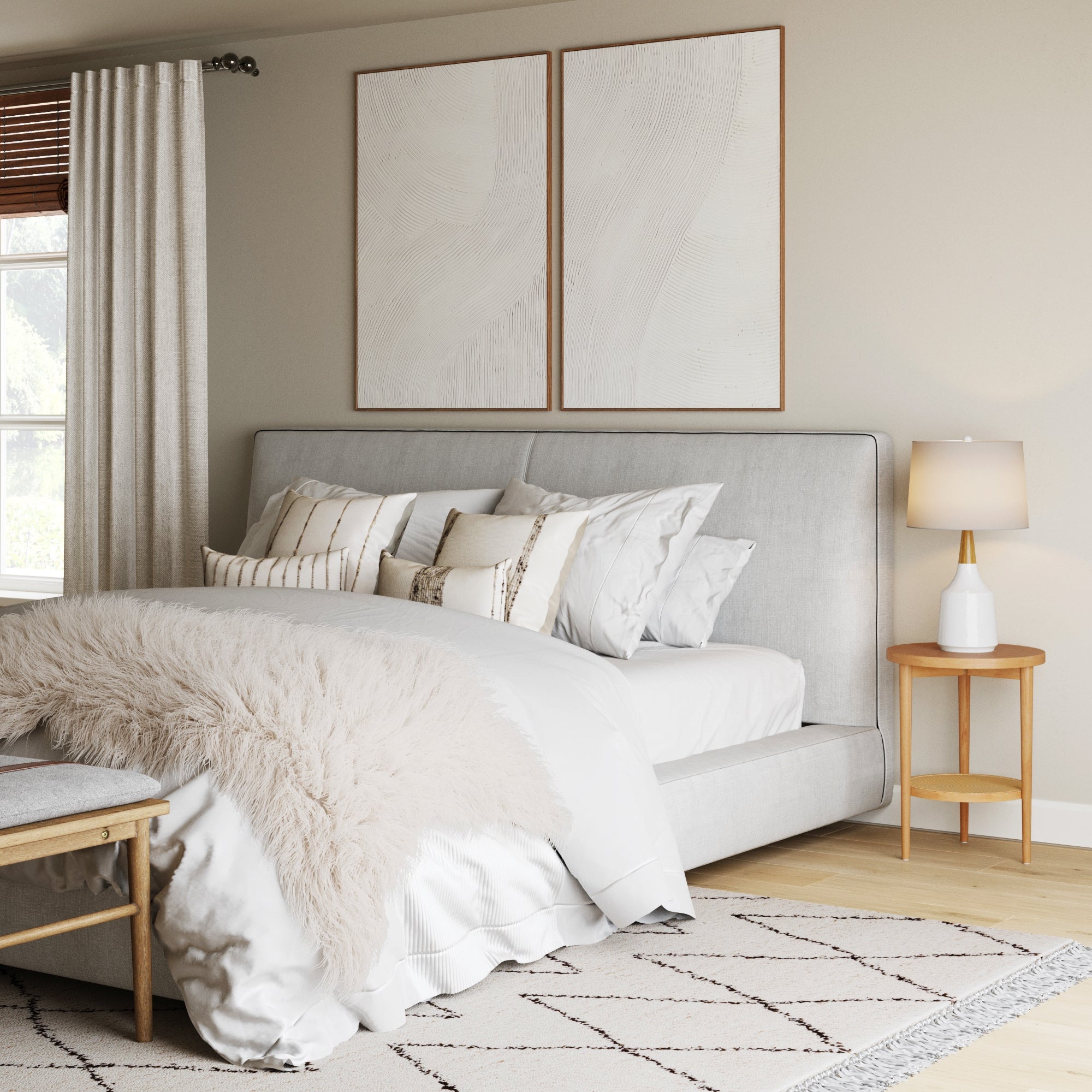 A modern bedroom features a neatly made bed with white and beige bedding, a faux fur throw, and decorative pillows. Beside the bed is the Nathan James Wood & Rattan Round End Table in Warm Pine, with two abstract pictures hanging above.
