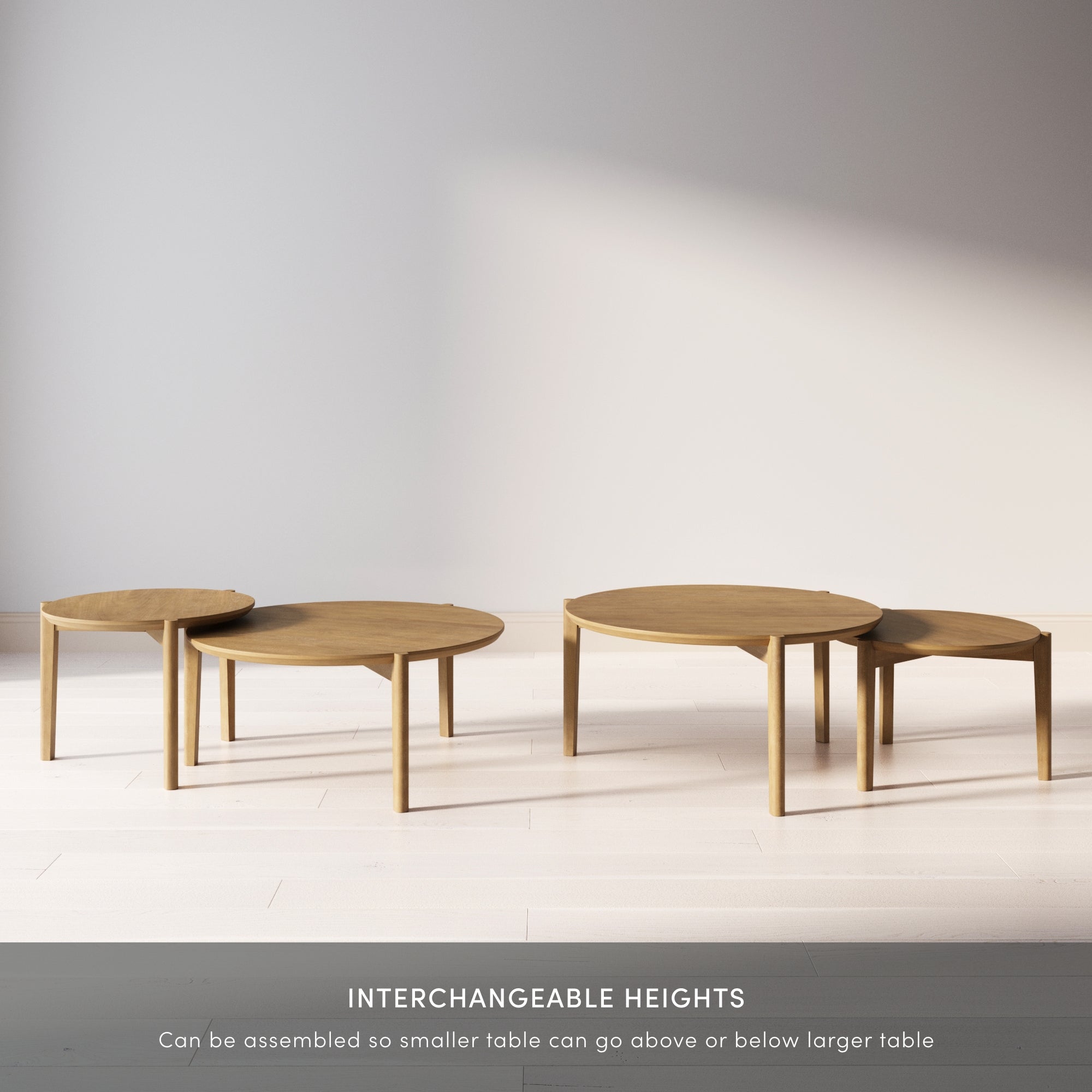 Four round wooden tables of varying heights are displayed on a light-colored floor. The tables are arranged so the smaller ones can fit above or below the larger ones. Text below describes their interchangeable heights.