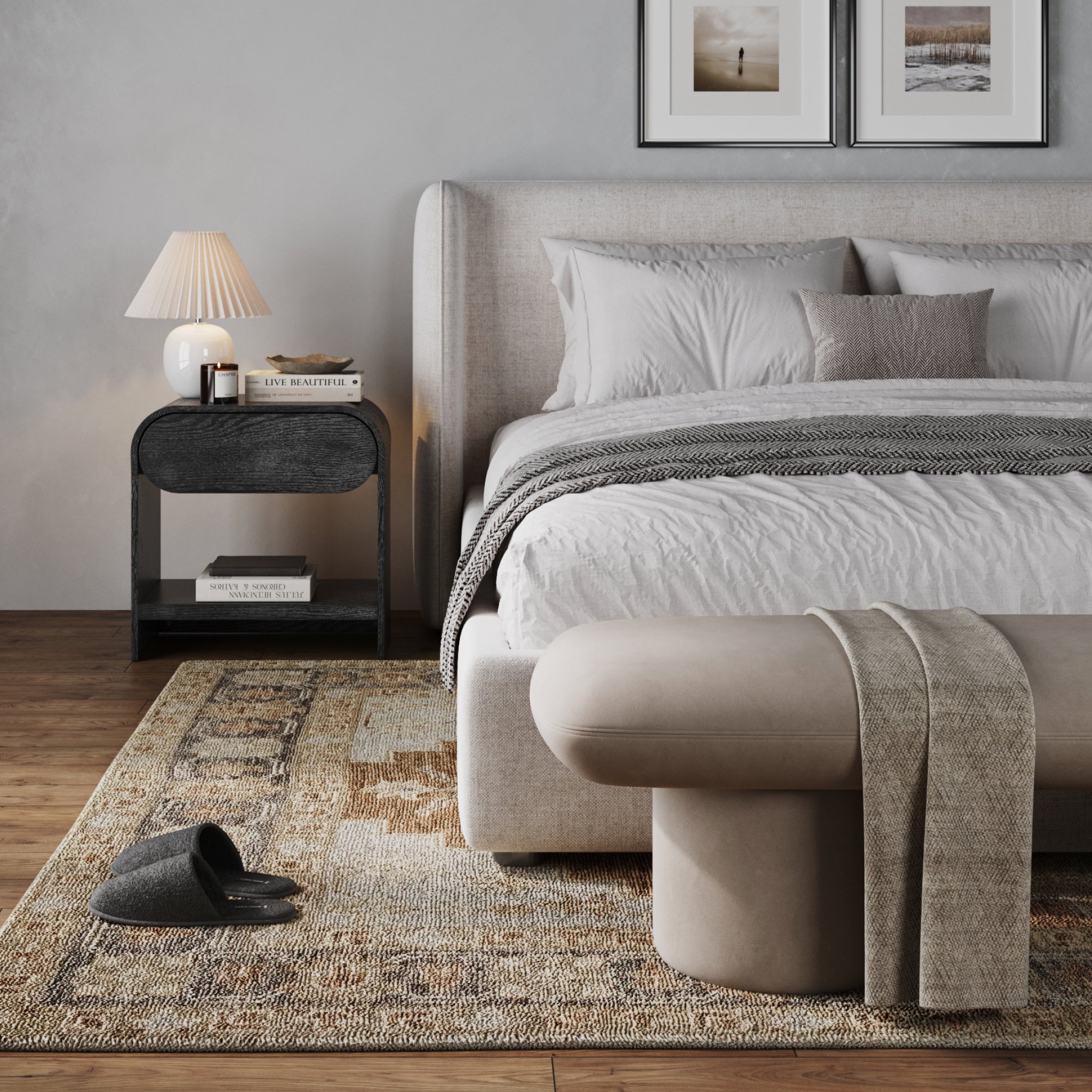 A modern bedroom with a neat bed, light headboard, gray and white bedding, a beige bench with throw, and the Nathan James Mid-Century Wood Arched Nightstand in Black Oak topped with a lamp and books, plus slippers on a patterned rug.