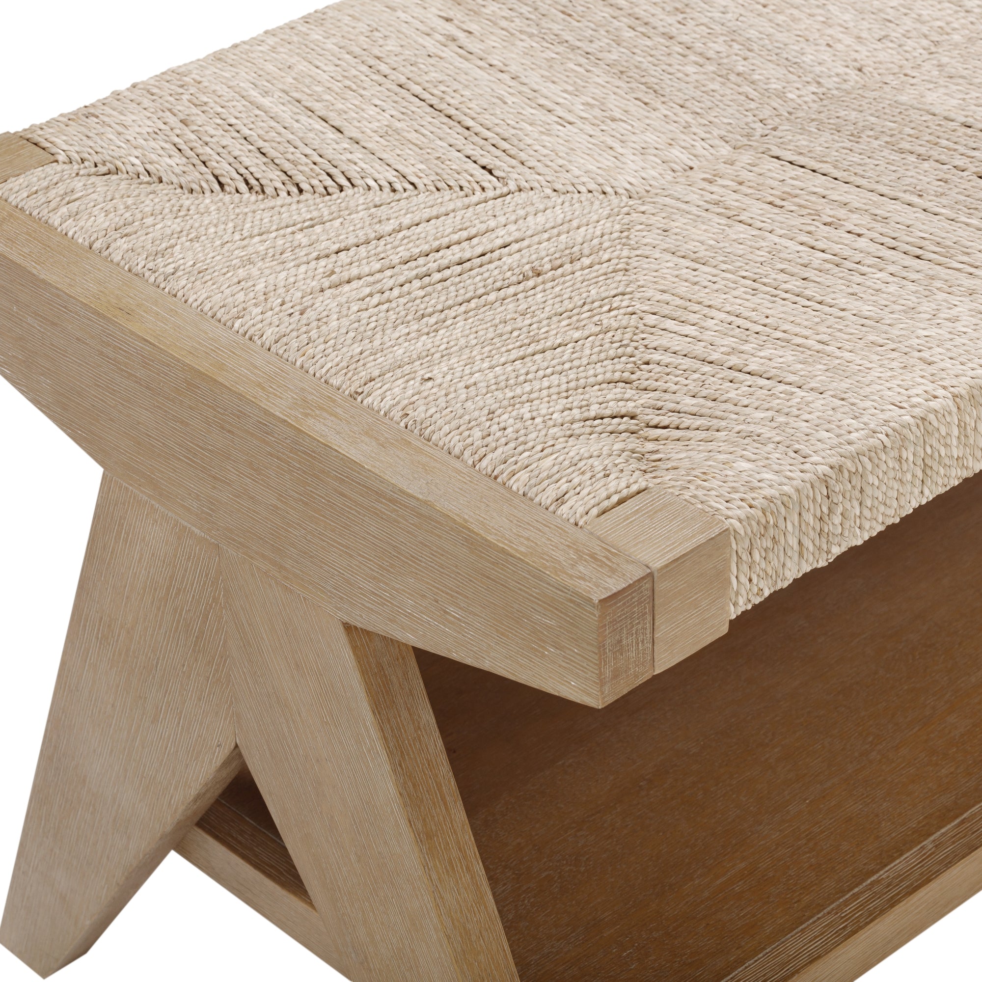 Close-up of a wooden bench featuring a woven natural fiber seat with a geometric pattern. The bench has a light wood finish and sturdy, angled legs.
