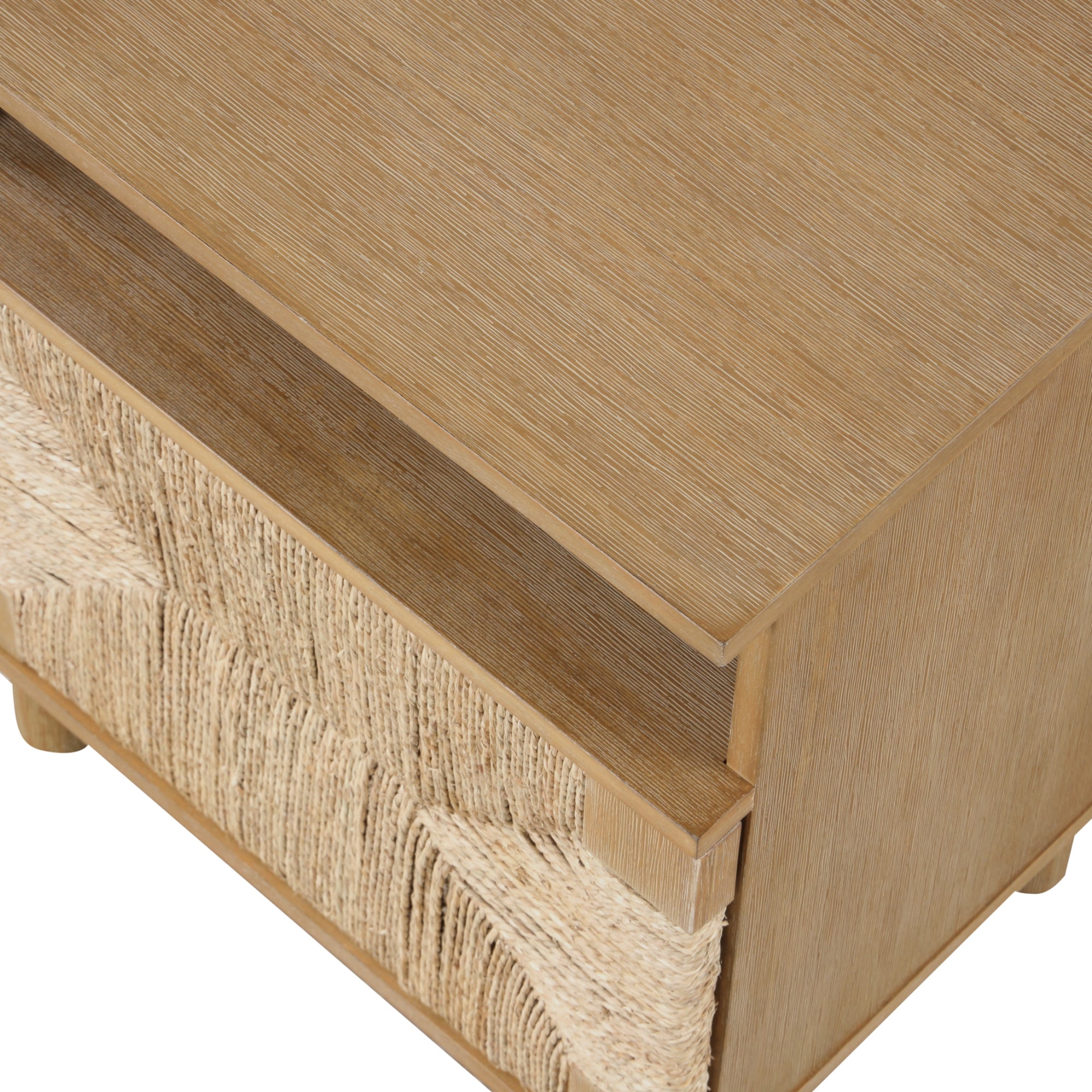Close-up, angled view of a wooden nightstand or side table with a textured woven pattern on the drawer front and a smooth, natural wood finish on the surfaces.