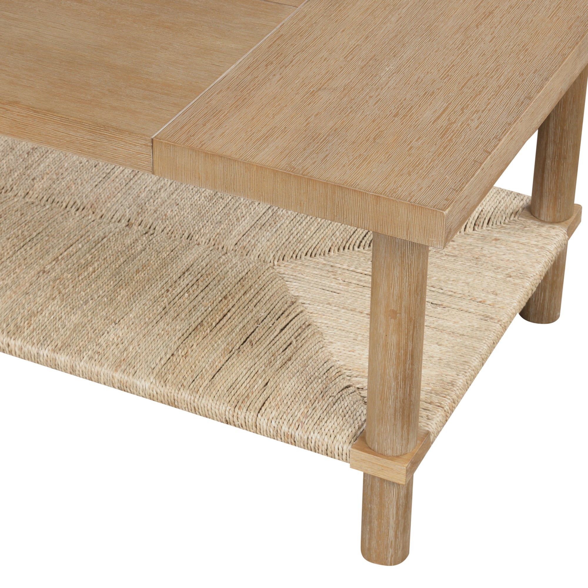 Close-up of a wooden table with square legs and a woven lower shelf made from natural fibers. The table top and shelf showcase a light wood finish.