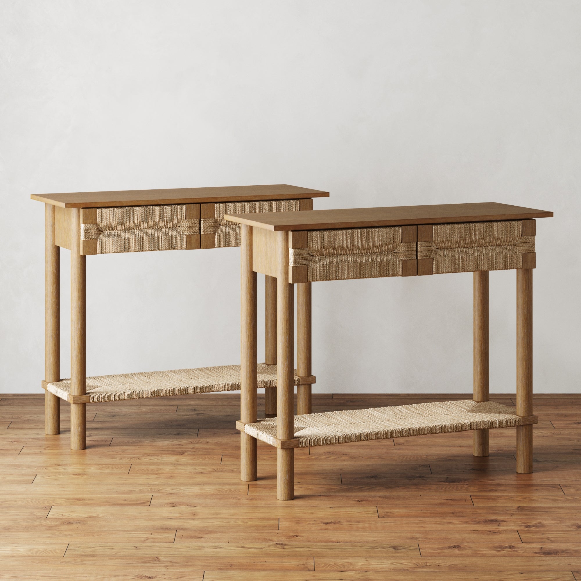 The Nathan James Boho Seagrass Console Tables (Set of 2) feature woven rope-detailed drawers and a seagrass shelf, shown on a hardwood floor against a white background.