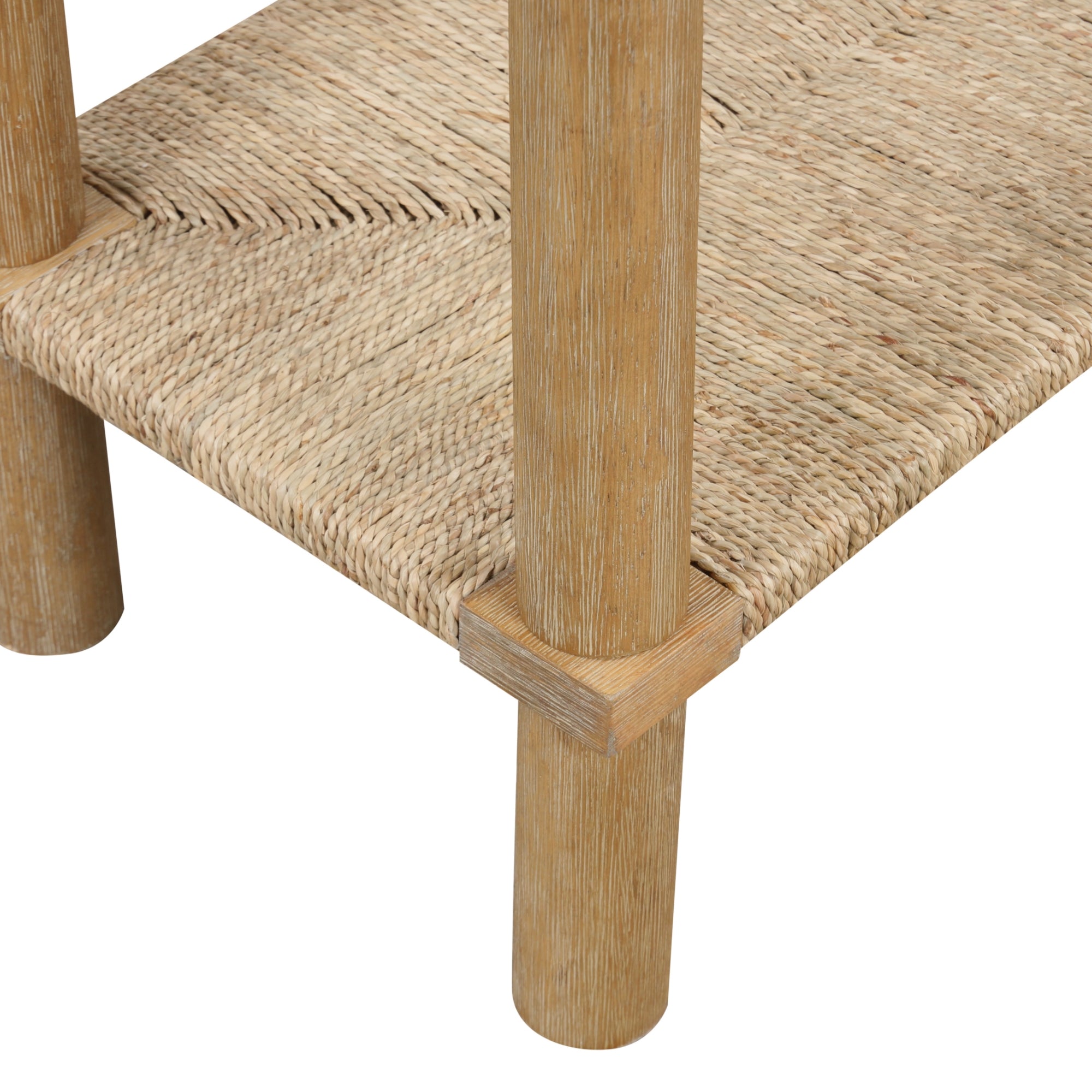 Close-up of a wooden furniture piece showing rounded legs and a woven rattan shelf. The texture of the wood and the detailed weaving of the shelf are clearly visible.