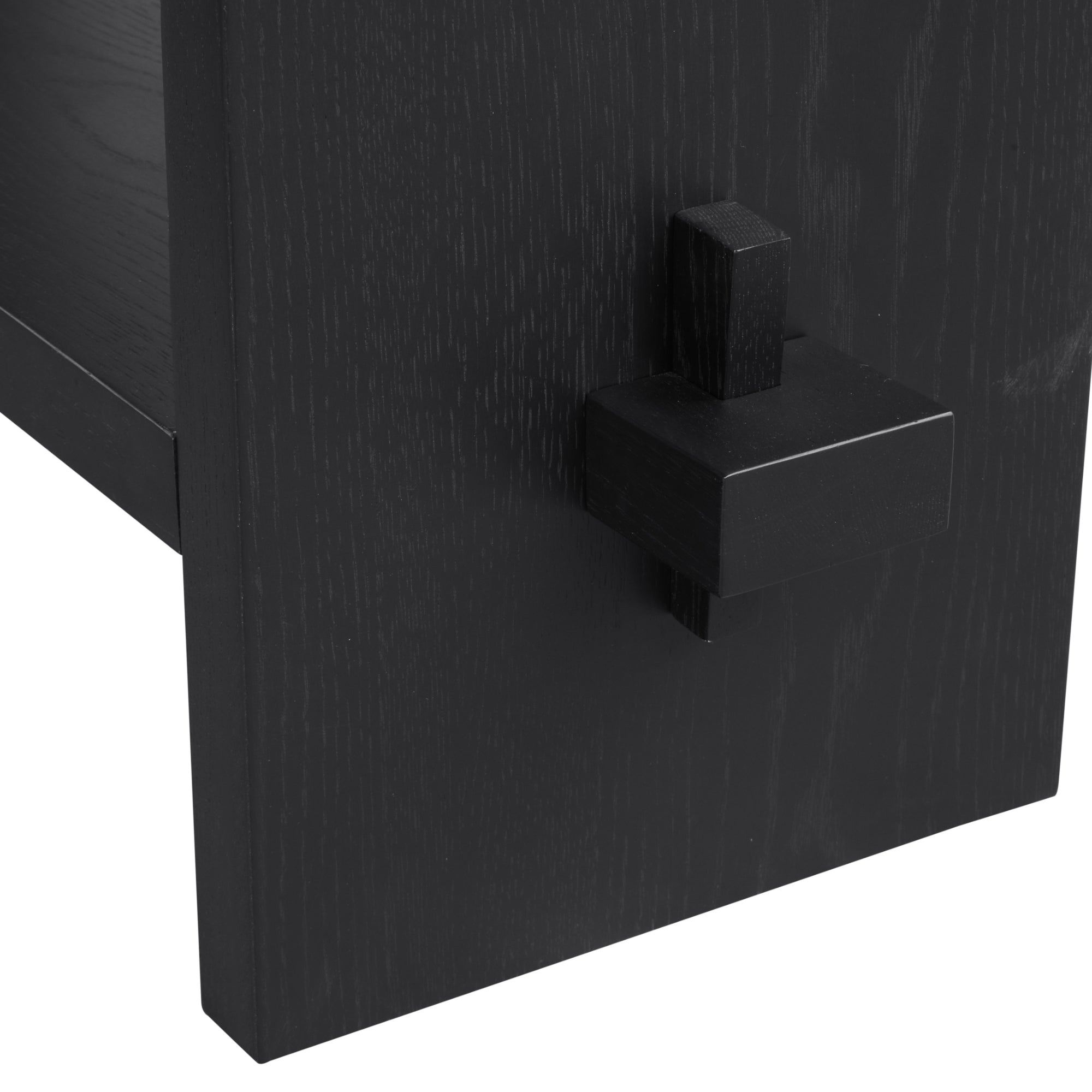 Close-up of a black wooden table or furniture piece with a distinctive square, block-shaped joint or decorative accent attached to the leg.