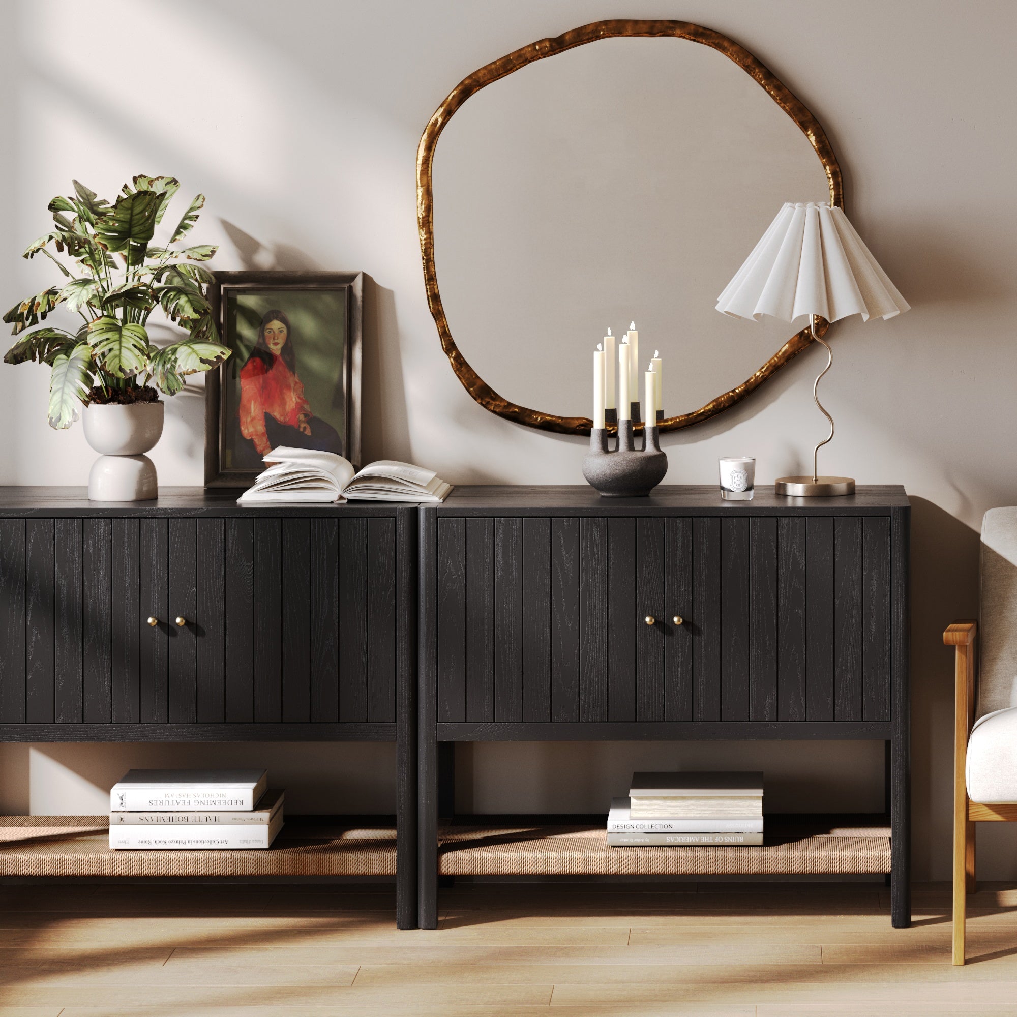 A modern living room featuring the Nathan James Mid-Century Grooved Door Storage Cabinet in Black Oak, decorative plants, a framed portrait, an open book, a round gold-framed mirror, candles, a white lamp, and neatly arranged books below.