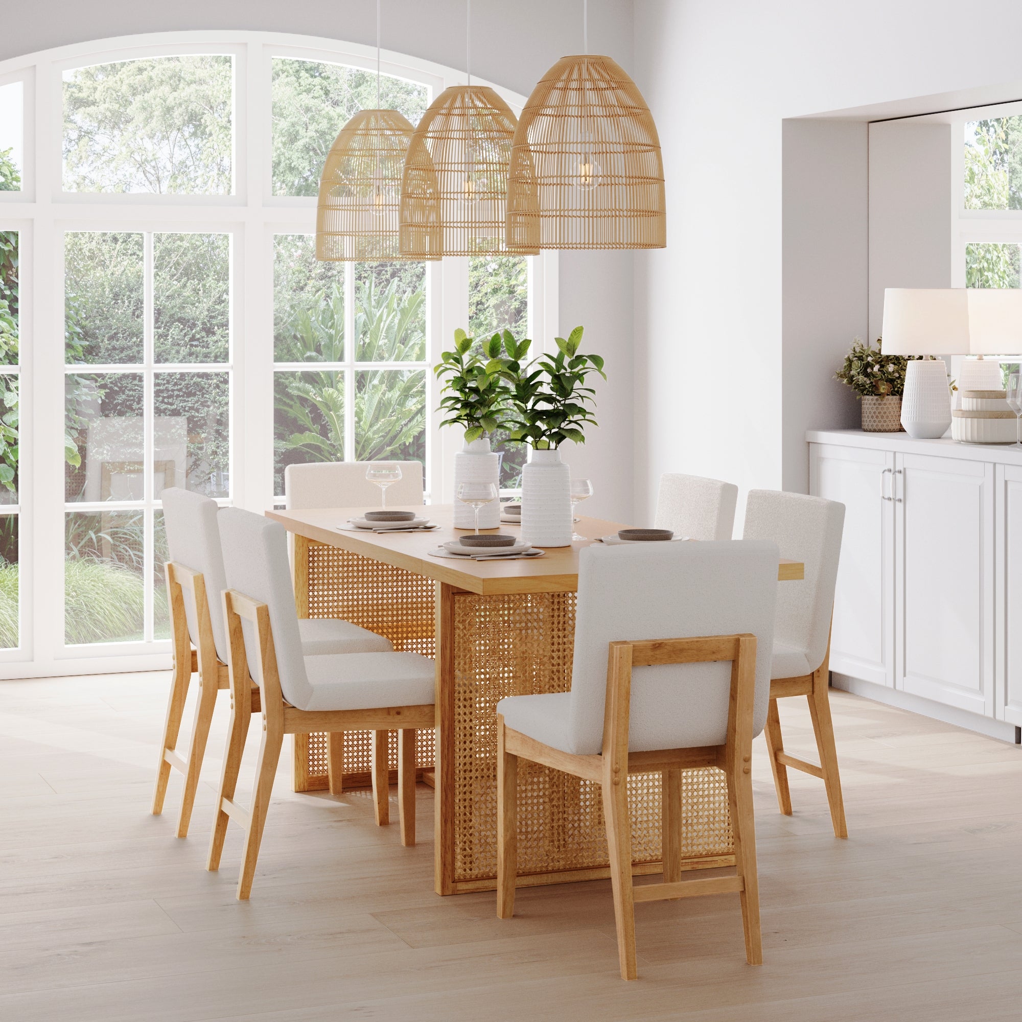 A bright dining room features the Nathan James Bohemian Wood & Boucle Dining Set (6 Chairs), three woven pendant lights, green plants, and large windows for natural light. Neutral decor and minimalist style complete the space.