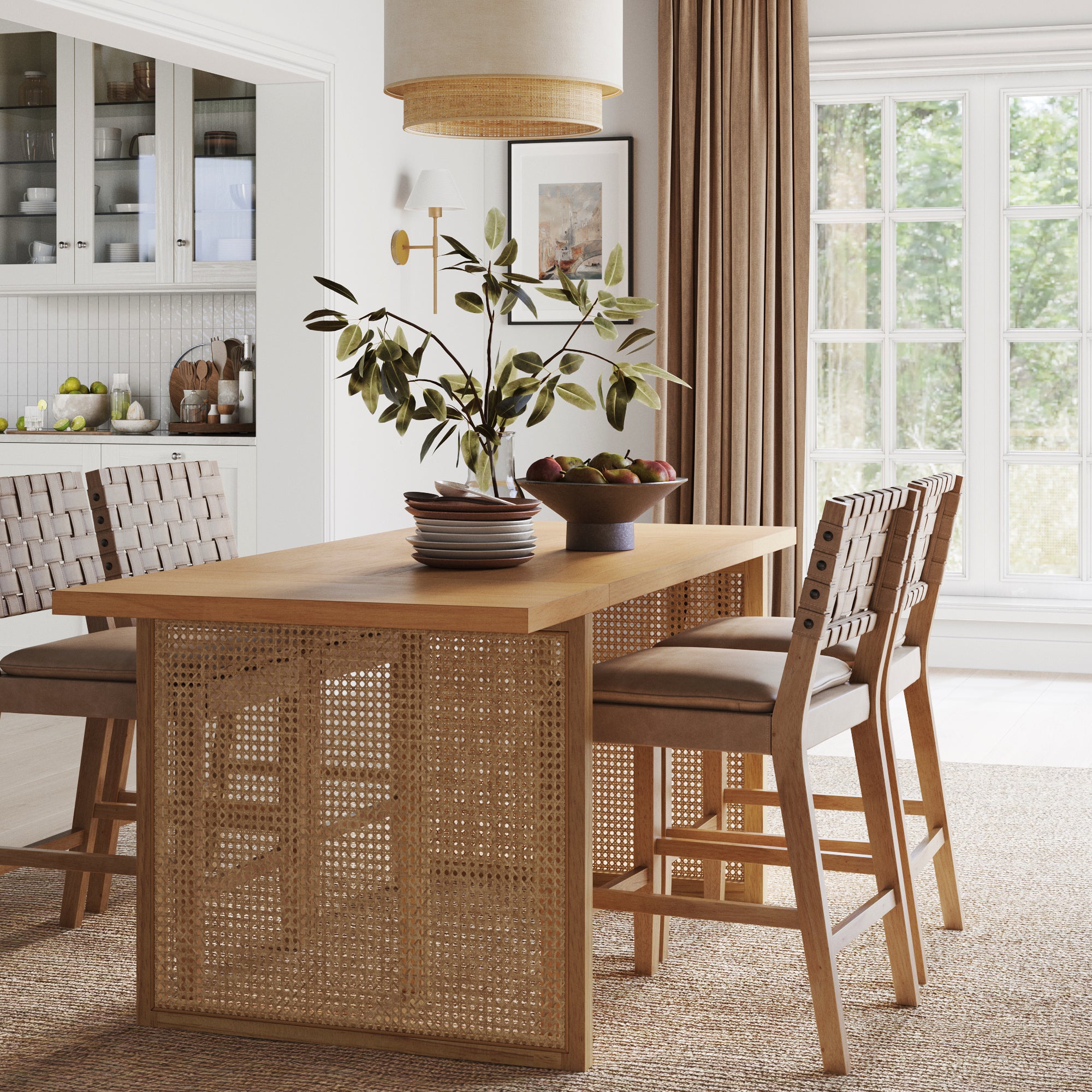 A modern dining room with a wooden table, woven chairs, a vase with green branches, a bowl of fruit, and neutral decor. Large windows let in natural light, and the space has a warm, inviting atmosphere.