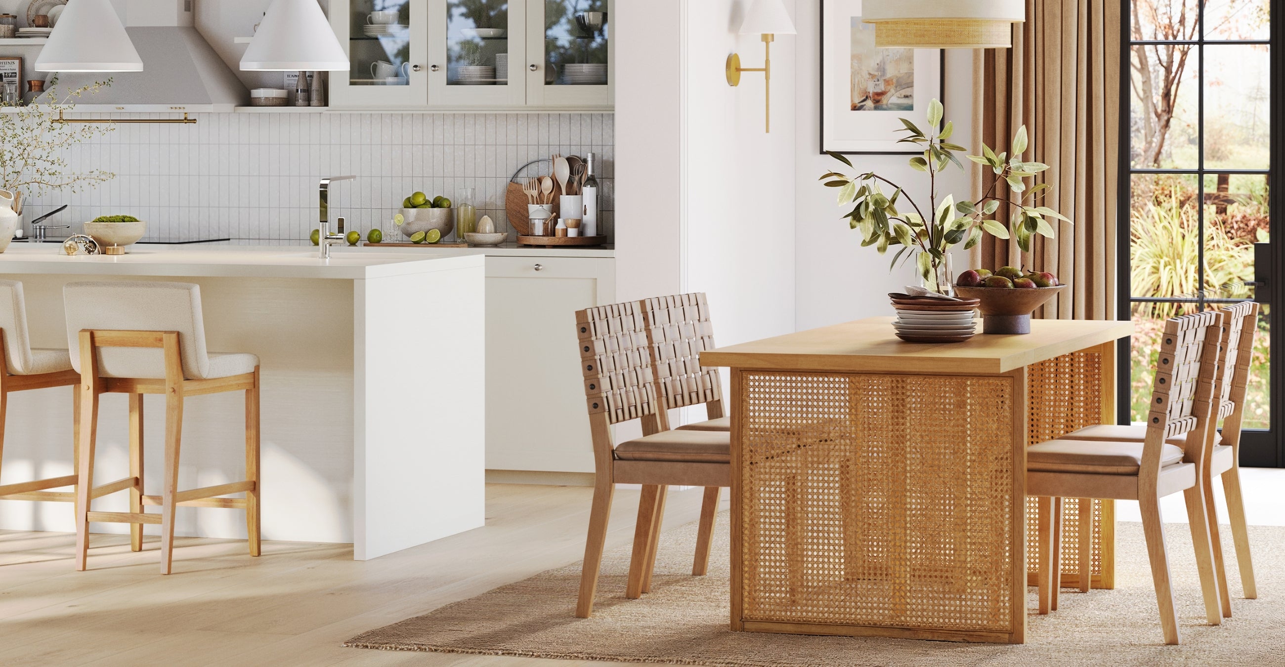 A modern dining area with a wooden table, four woven chairs, a bowl of fruit, and a kitchen with stools and pendant lights in the background. Sunlight streams in through large glass doors.