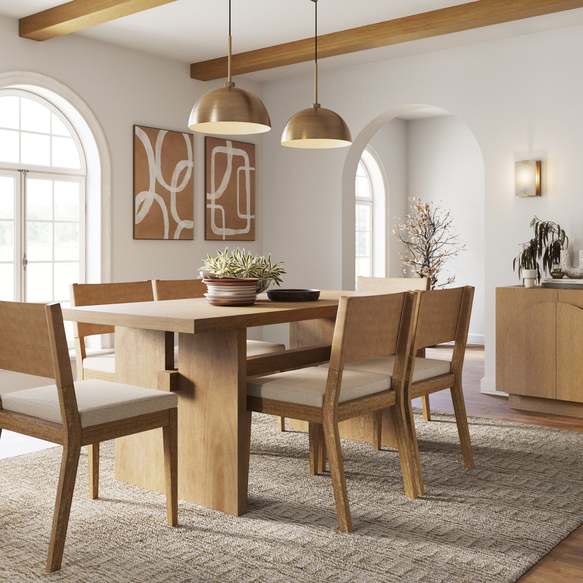 A modern dining room with a wooden table, six matching chairs, two pendant lights, abstract wall art, large windows, and neutral decor. A centerpiece with plants sits on the table.