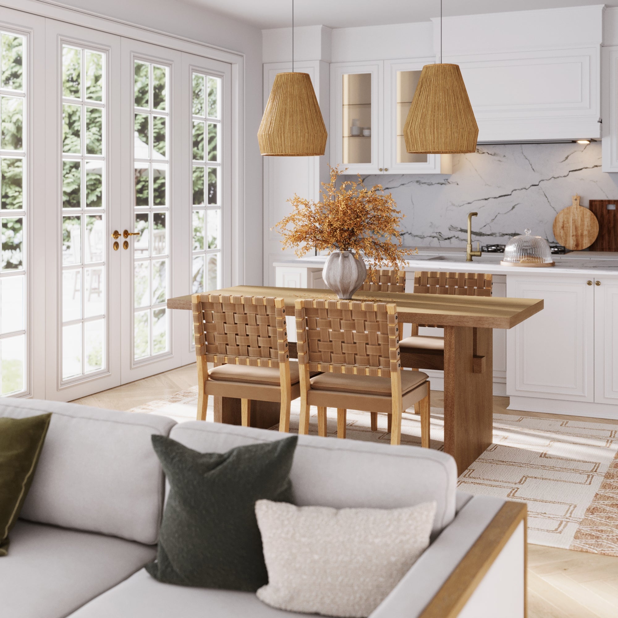 A modern kitchen and dining area includes white cabinets, a solid wood table, and faux leather chairs from the Nathan James Mid-Century Woven Dining Set in light brown, woven pendant lights, a vase with dried flowers, a light gray sofa with green and cream cushions, and bright windows.