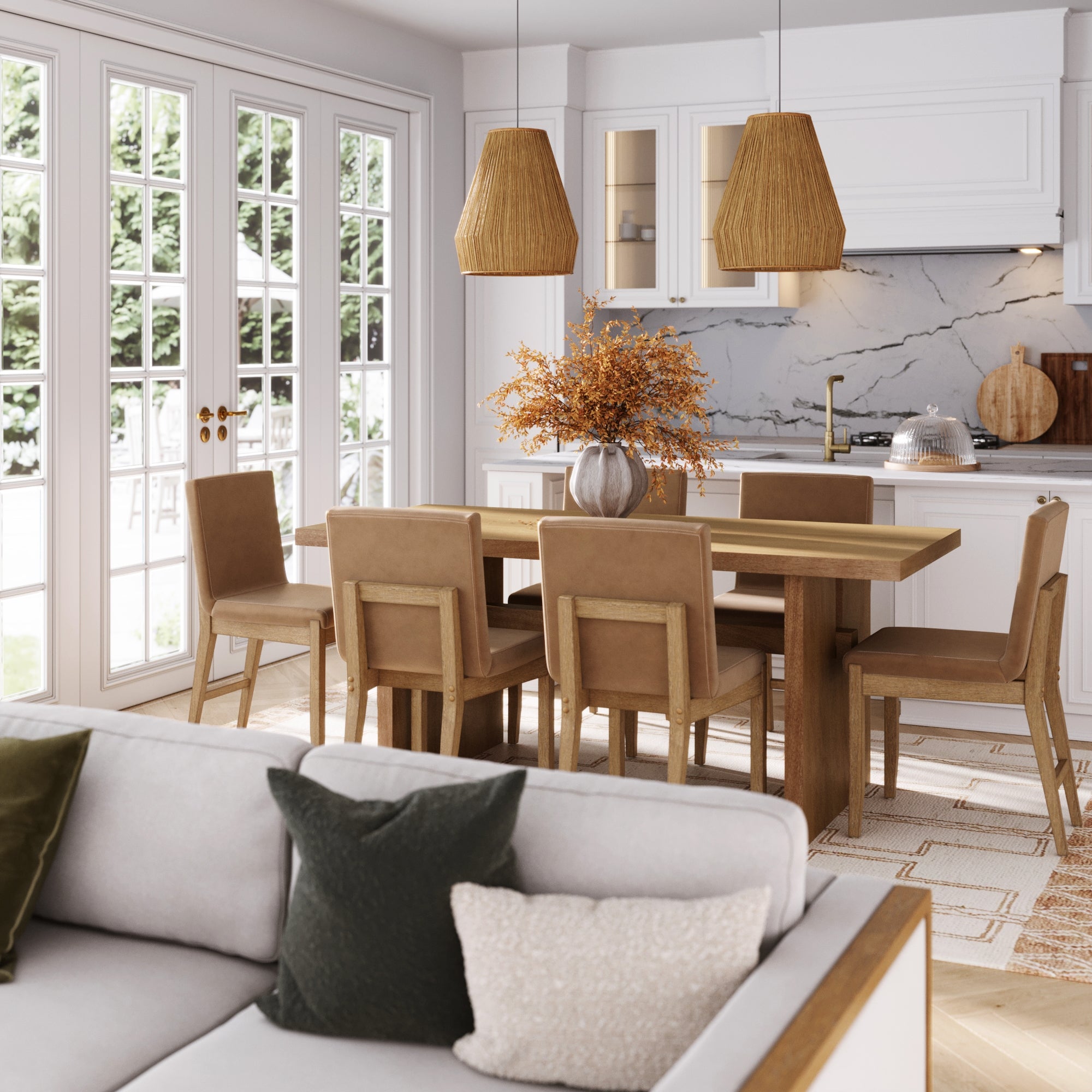 A modern dining area features a Nathan James Wood Modern Farmhouse Dining Table (seats 6), six tan chairs, a vase with dried flowers, and pendant lights. In the background are a white kitchen and large windows overlooking greenery; a cushioned sofa sits in front.