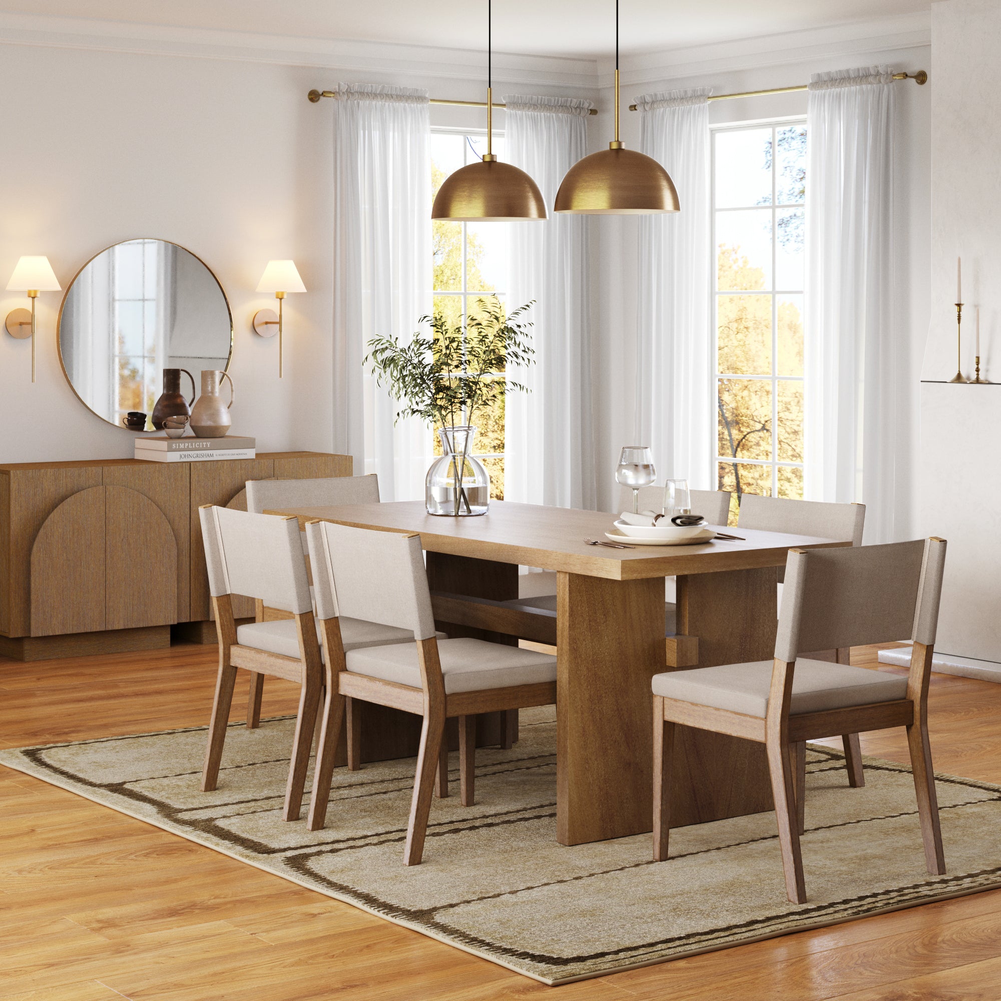 A modern dining room with a wooden table, six upholstered chairs, a neutral rug, large windows with white curtains, gold pendant lights, and a sideboard with a round mirror and decorative items.