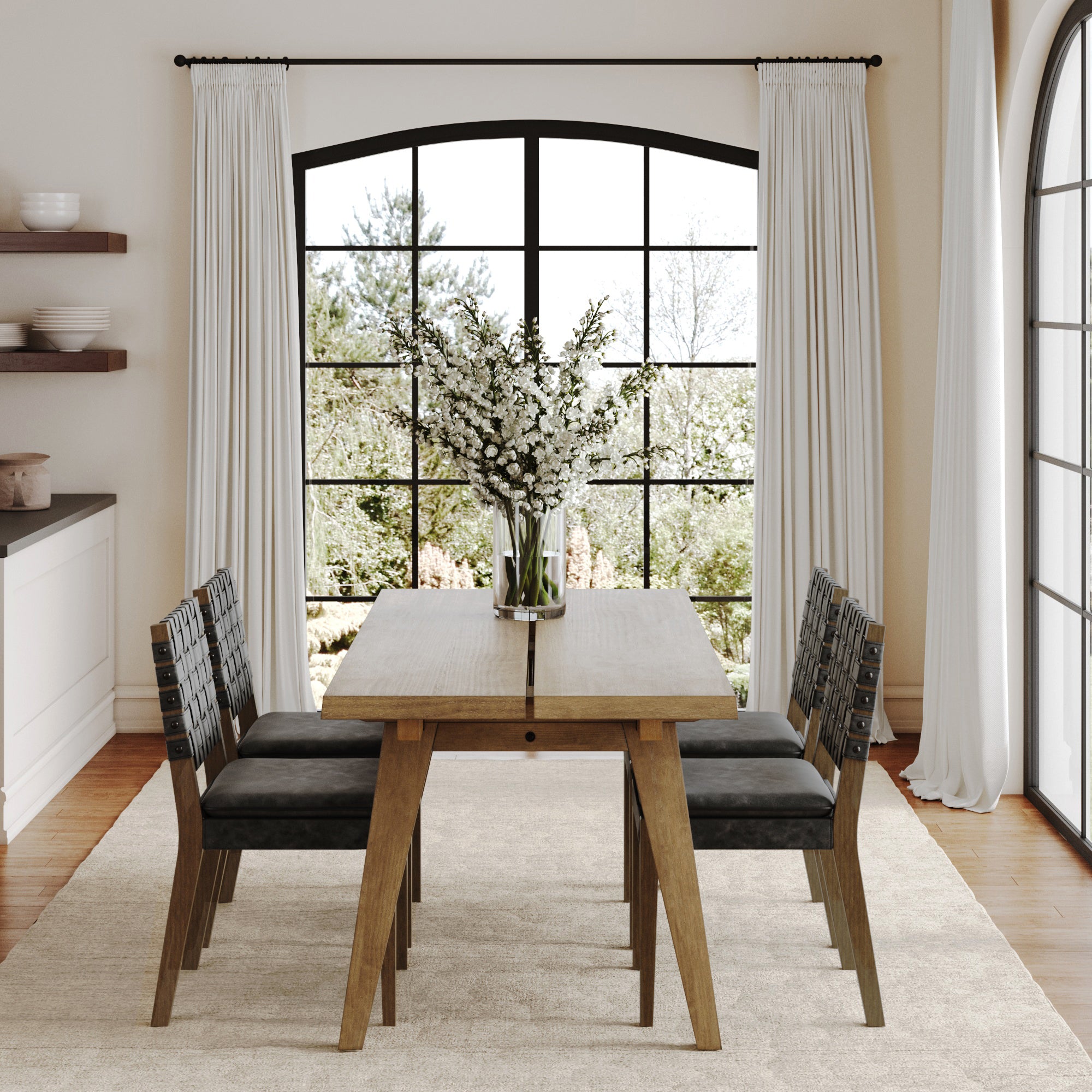 The Nathan James Mid Century Faux Leather 4 Chairs Dining Set in black sits on a light rug by large arched windows with white curtains, featuring a glass vase with white flowers at the center of the table.