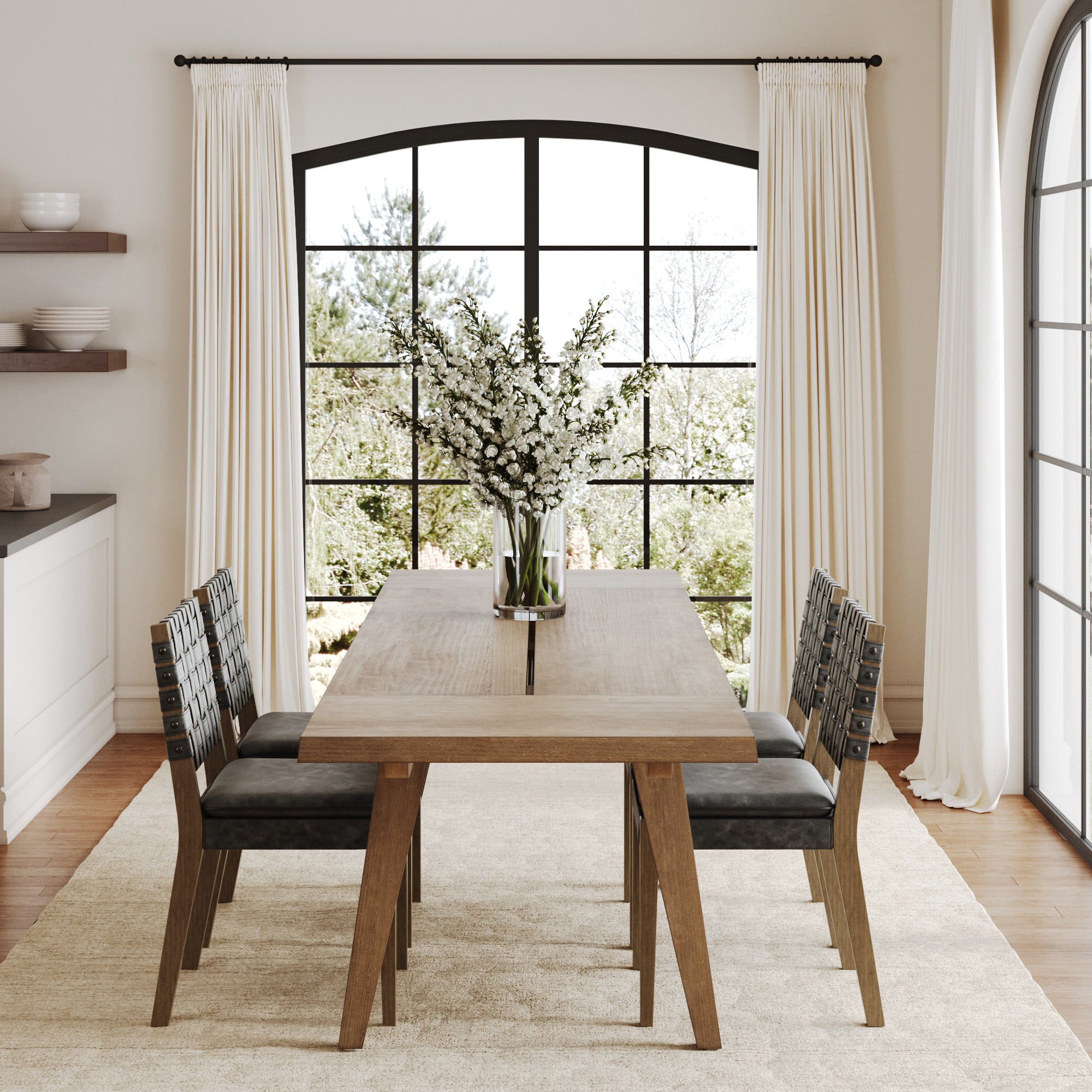 A modern dining room features the Nathan James Extendable Dining Set with Black Dining Chairs (set of 4), a vase of white flowers, large windows with white curtains, and sunlight streaming in for a bright and airy feel.