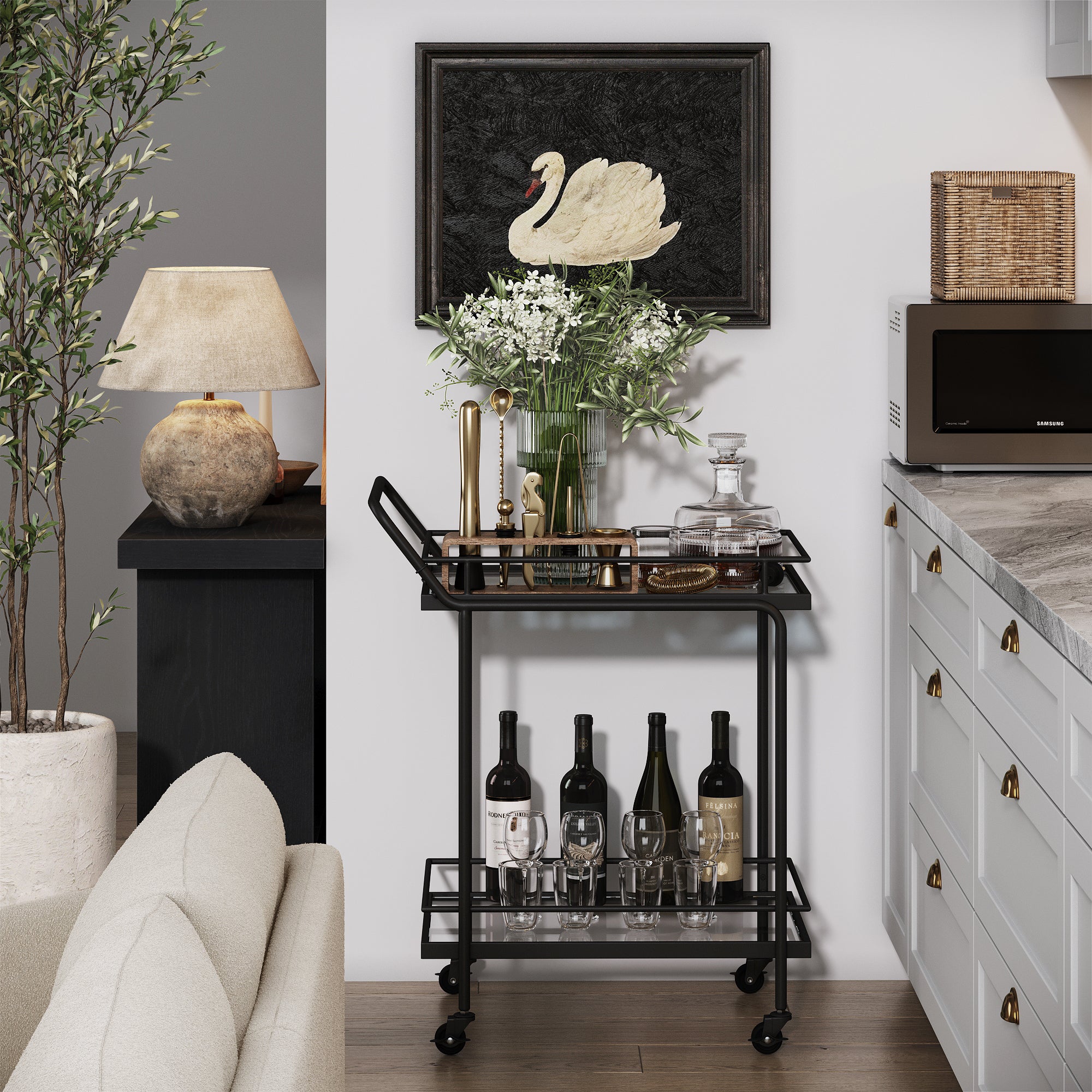 A black bar cart with bottles, glassware, and a vase of flowers stands against a wall, beneath a framed swan artwork. The cart is next to a kitchen counter and a lamp, with a potted plant nearby.