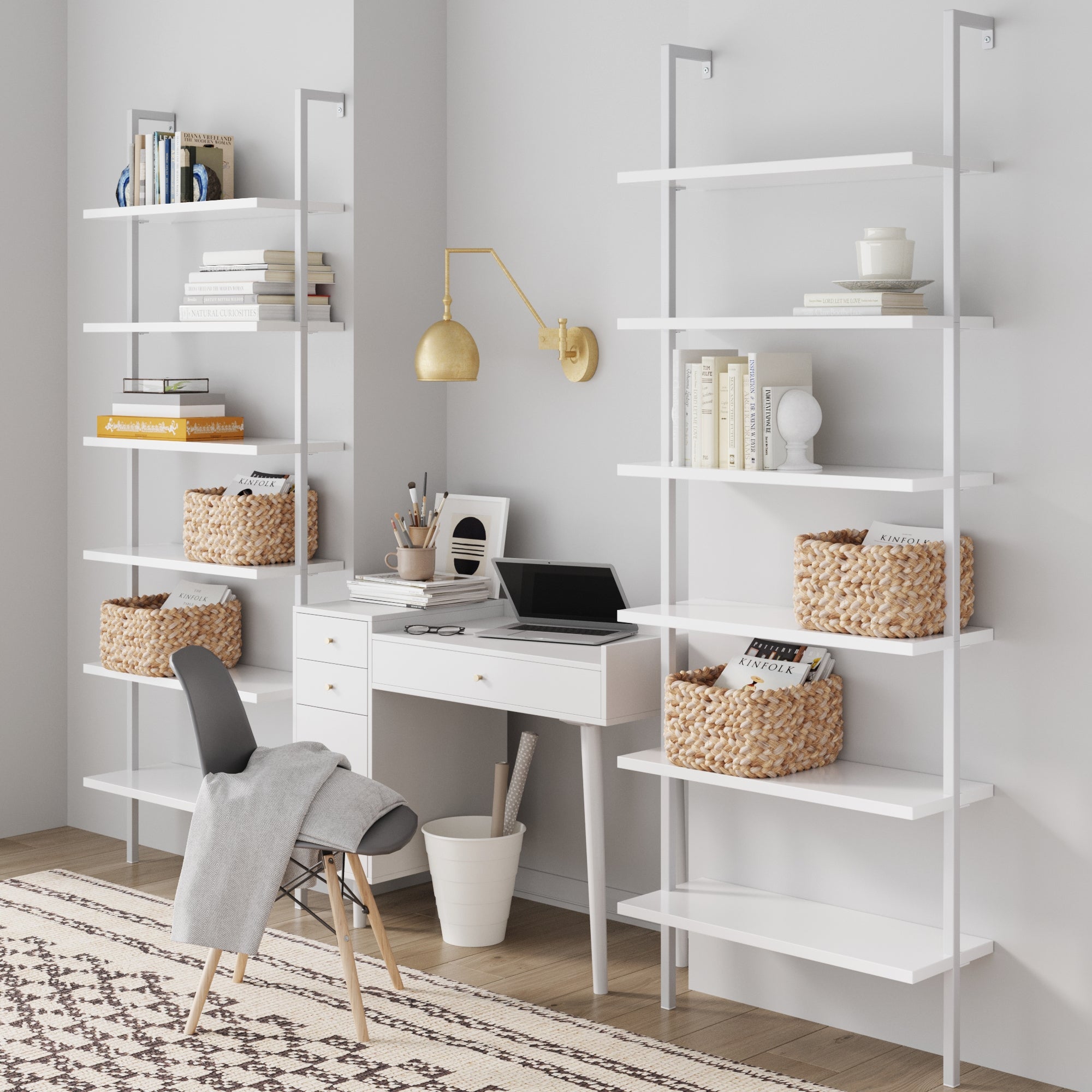 A modern home office with the Nathan James Mid-Century Modern White Wall Desk, open shelves with books and baskets, a black and white chair, laptop, gold wall lamp, and geometric rug on wood floors.