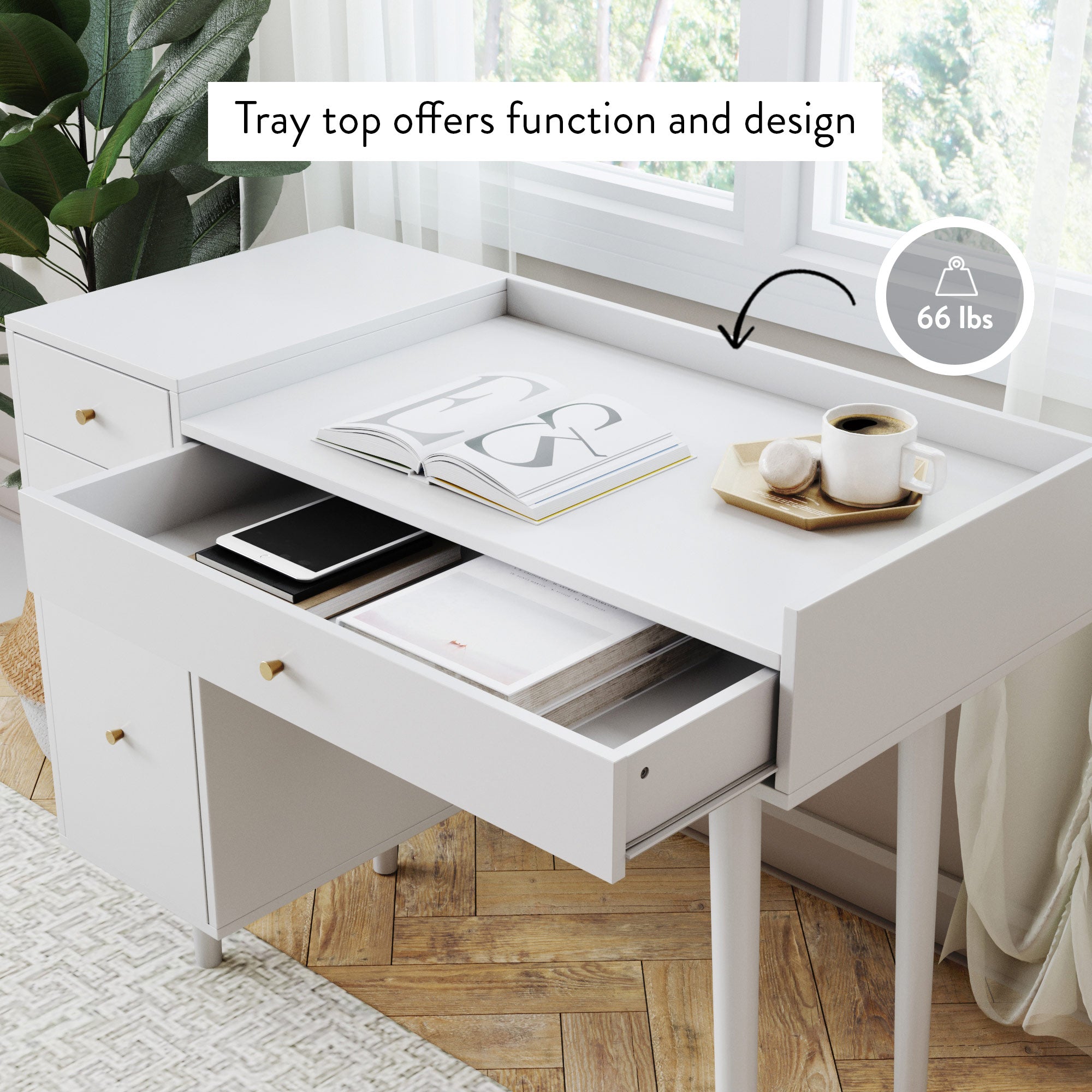 A modern white desk with drawers sits by a window. The tray top holds books, a notebook, and coffee, labeled “Tray top offers function and design.” An icon shows the tray supports up to 66 lbs.