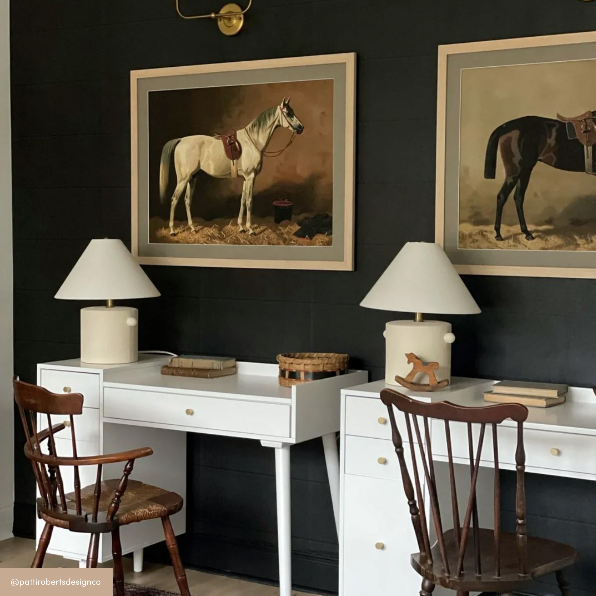 Two wooden chairs sit in front of two white desks with table lamps and books. Above each desk hangs a framed horse painting on a dark wall—one shows a white horse, the other a dark brown horse.