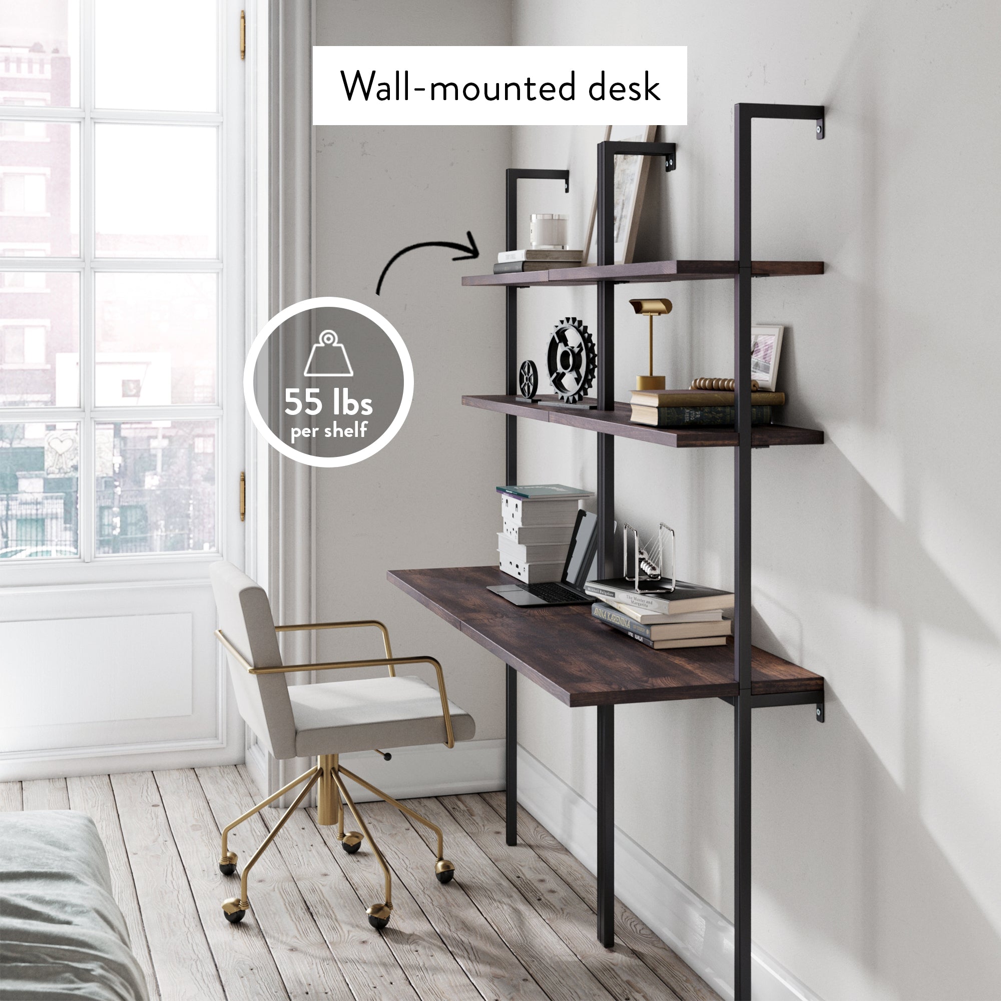 A wall-mounted desk with three dark wood shelves supported by black metal frames, styled with books and decor. A white and gold office chair sits in front; a label indicates each shelf holds up to 55 lbs. Large window on the left.